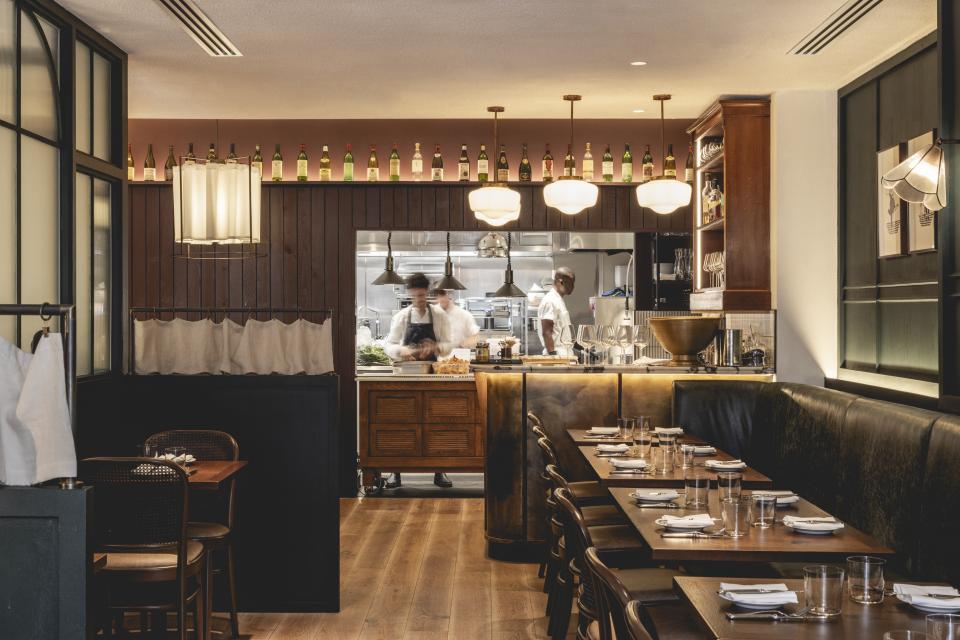 Stylish interior of Studio Found's Fitzrovia restaurant, blending Parisian chic with rustic British decor, featuring chefs at work.