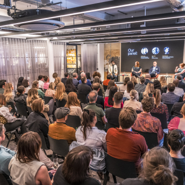 Panel discussion at the Future of Workplace seminar, with an audience engaged in a modern office setting.