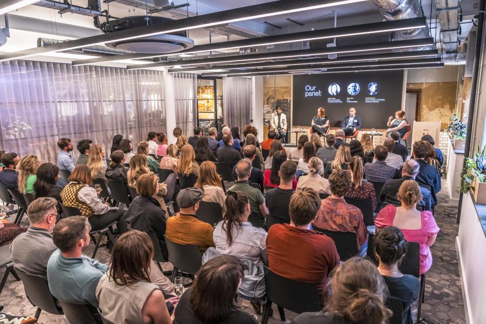 Panel discussion at the Future of Workplace seminar, with an audience engaged in a modern office setting.