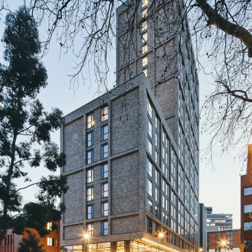 Modern student accommodation building designed by 74, showcasing sophisticated architecture and inviting amenity spaces in an urban setting.