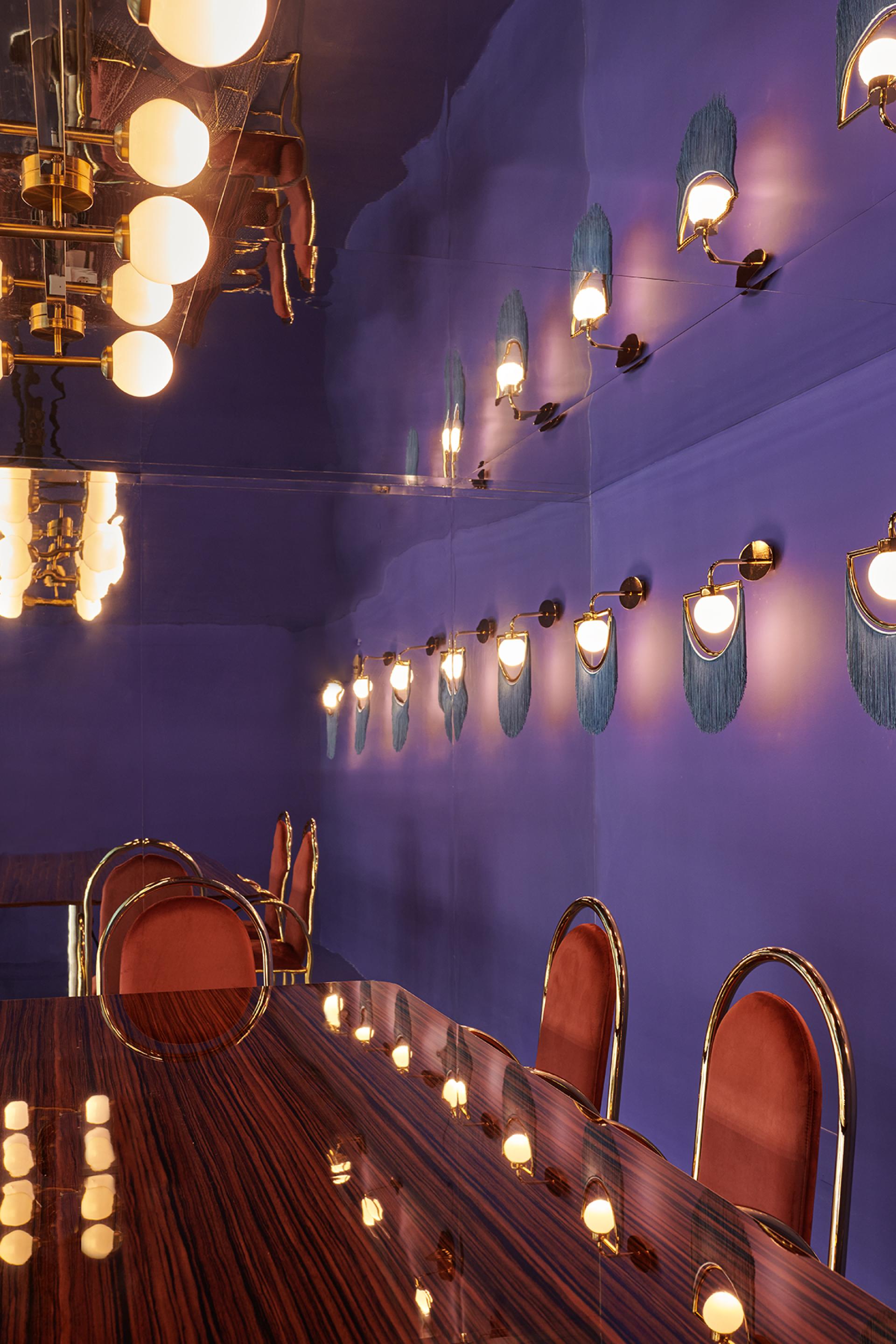 Vibrant coworking space in Valencia featuring a glossy purple wall, stylish lighting, and elegant seating designed for creativity.