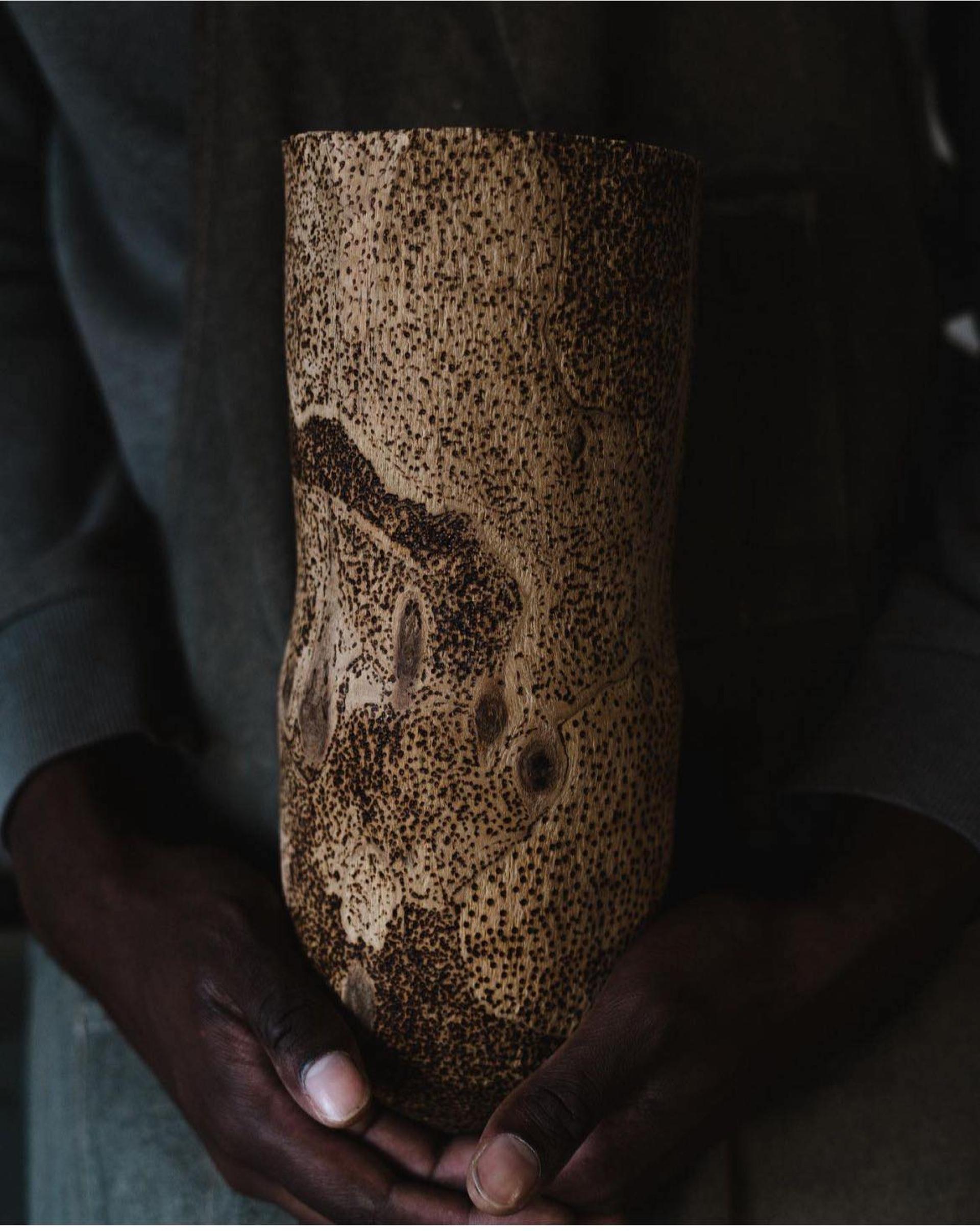 Handcrafted wooden vase with intricate textures held by a person, showcasing contemporary craft for the Collect 2025 event.