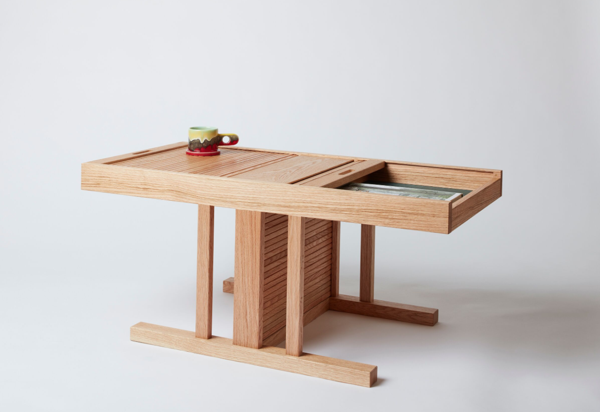 Sustainable wooden 'Useful Table' designed by students, featuring a storage compartment and a coffee cup on top.