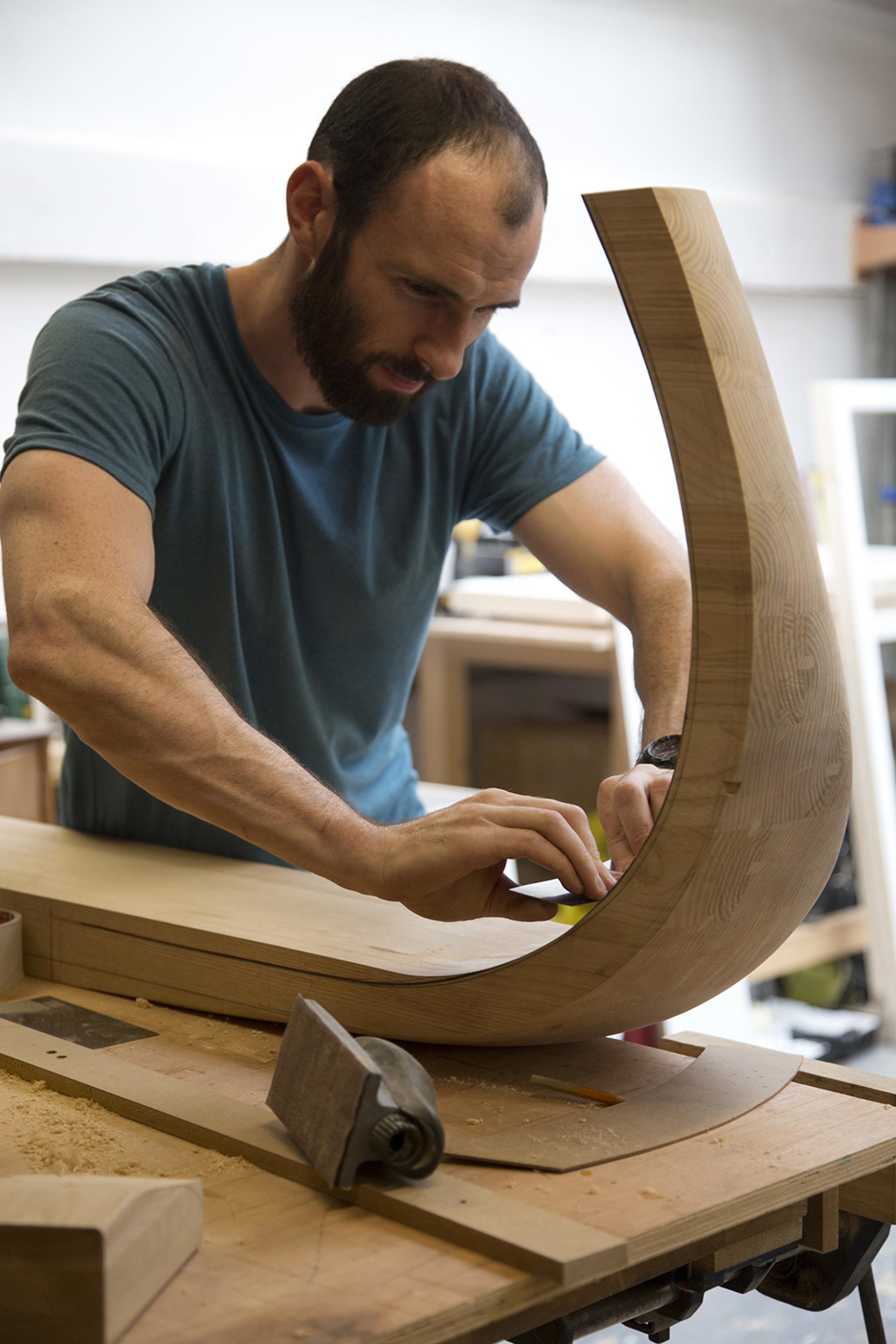 A craftsman meticulously shaping wood in a workshop, showcasing the artistry of Bristol's creative craft scene.