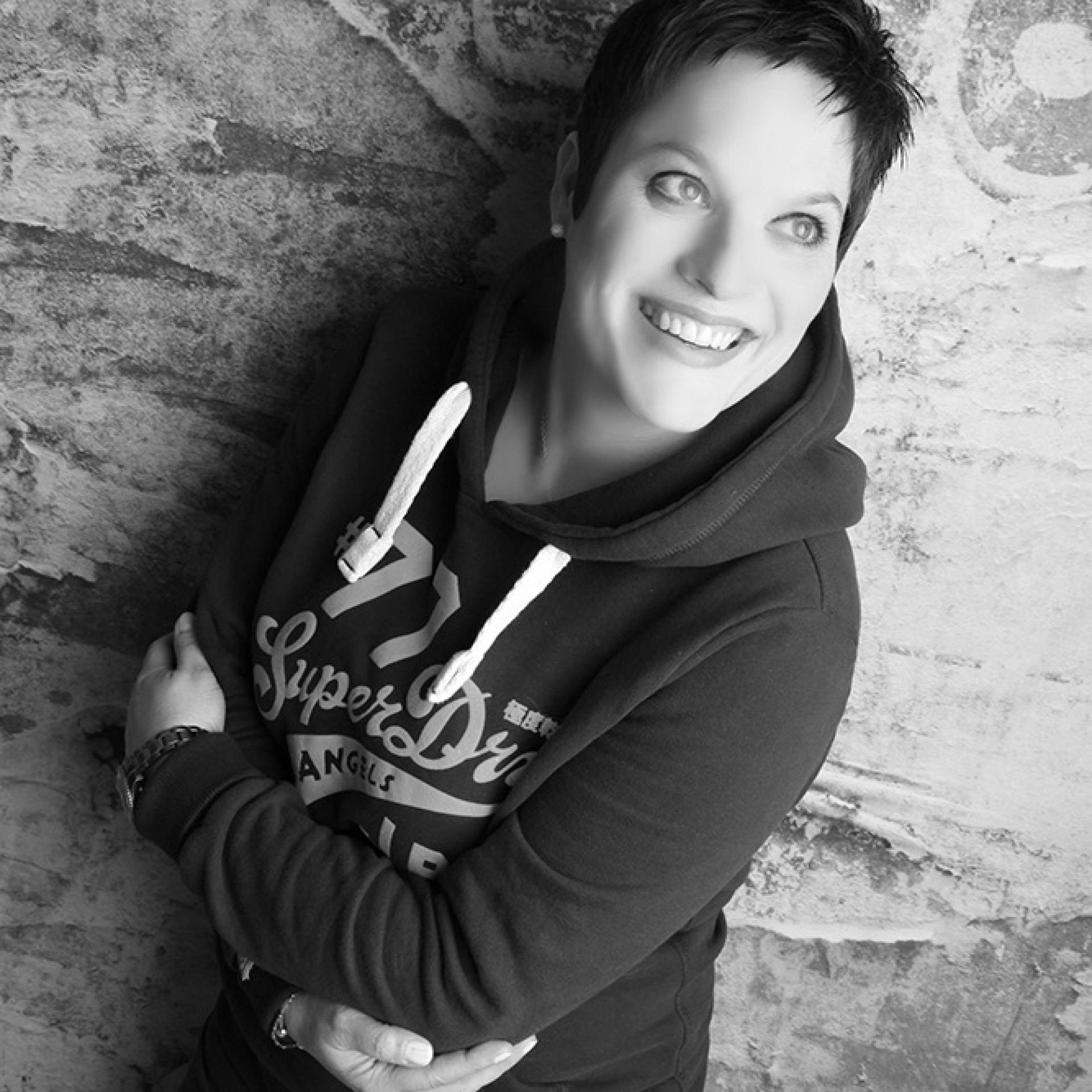 Creative director smiling against textured backdrop, representing Standing Space's approach to uplifting interior design and client collaboration.