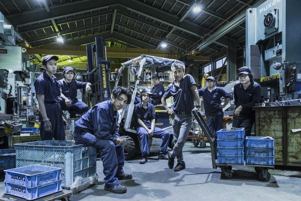 Craftsmen at work in Tsubame-Sanjo, showcasing traditional metal craftsmanship in a bustling workshop environment.