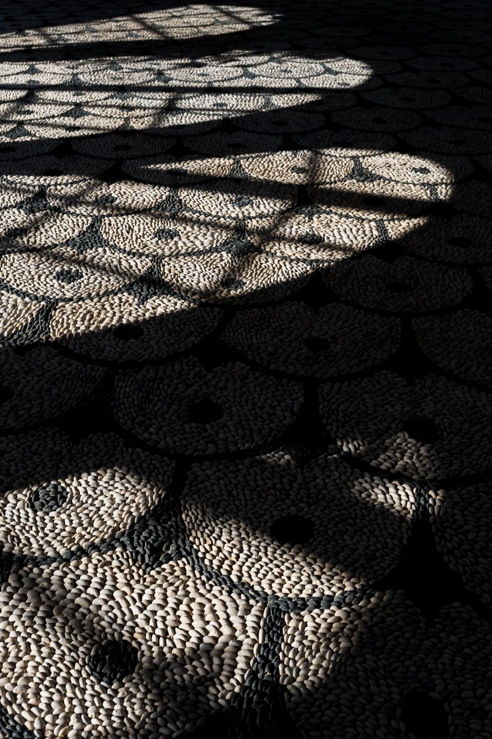 Shadows and light patterns create an artistic interplay over a textured surface, highlighting the beauty of design and light.