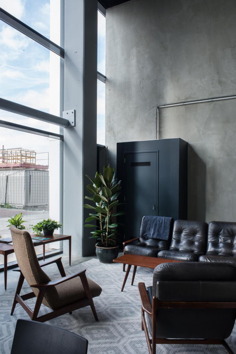 Sleek interior of HOP's Public Space in Amsterdam featuring minimalist furniture, greenery, and industrial-style elements.
