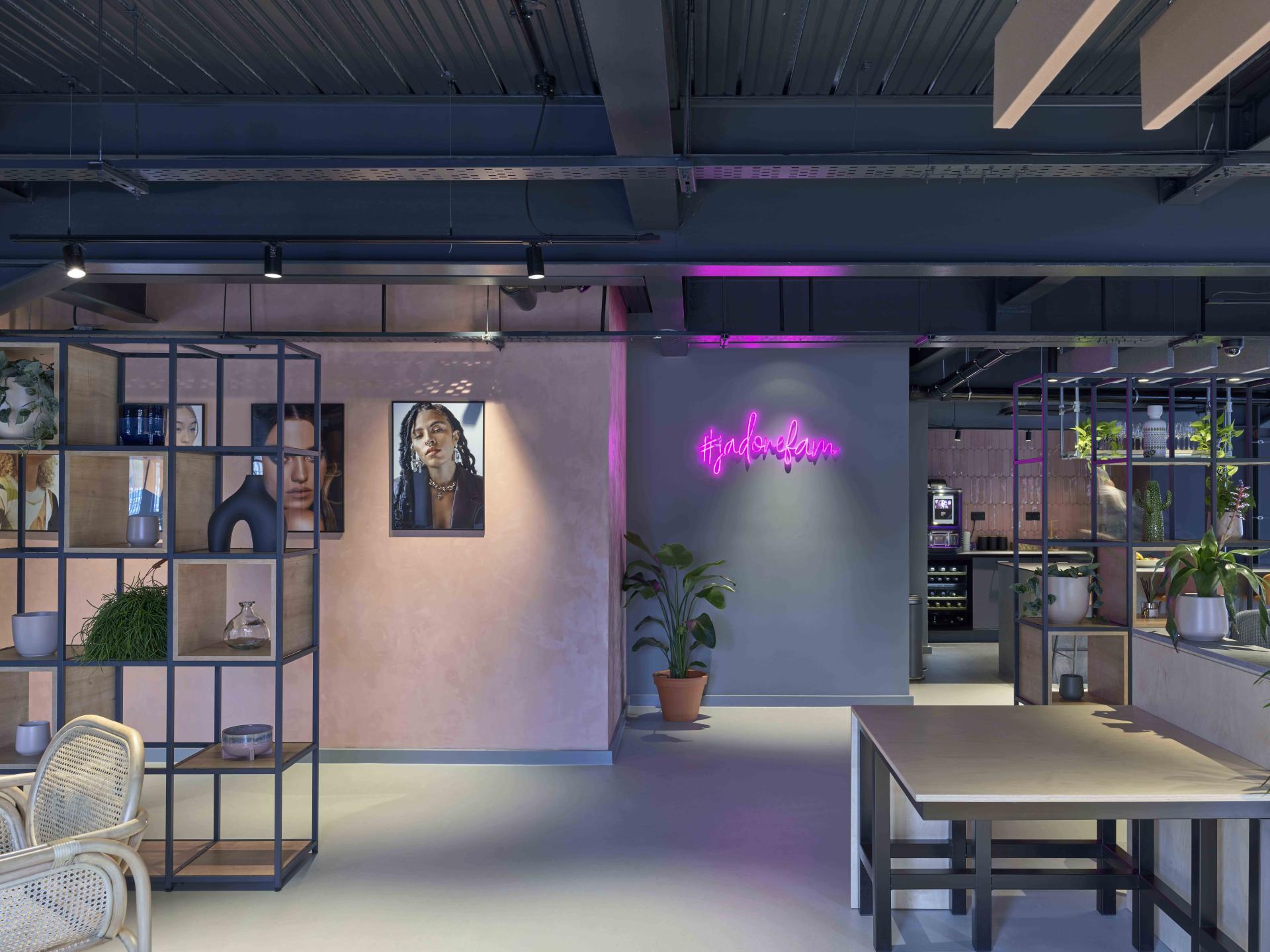 Stylish interior of J’adore Models' new headquarters featuring vibrant plants, artwork, and a neon sign.