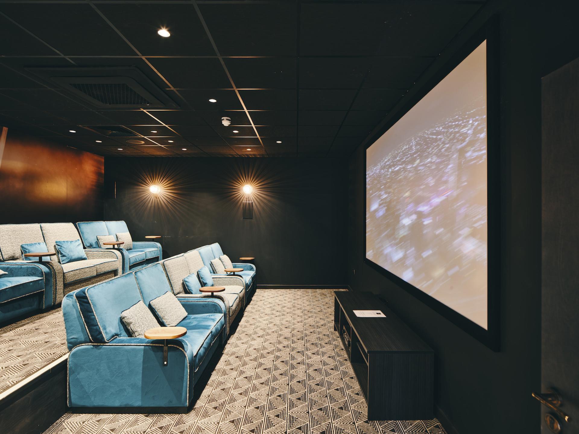 Sophisticated student cinema space featuring plush blue seating and a large projection screen in a modern interior design.