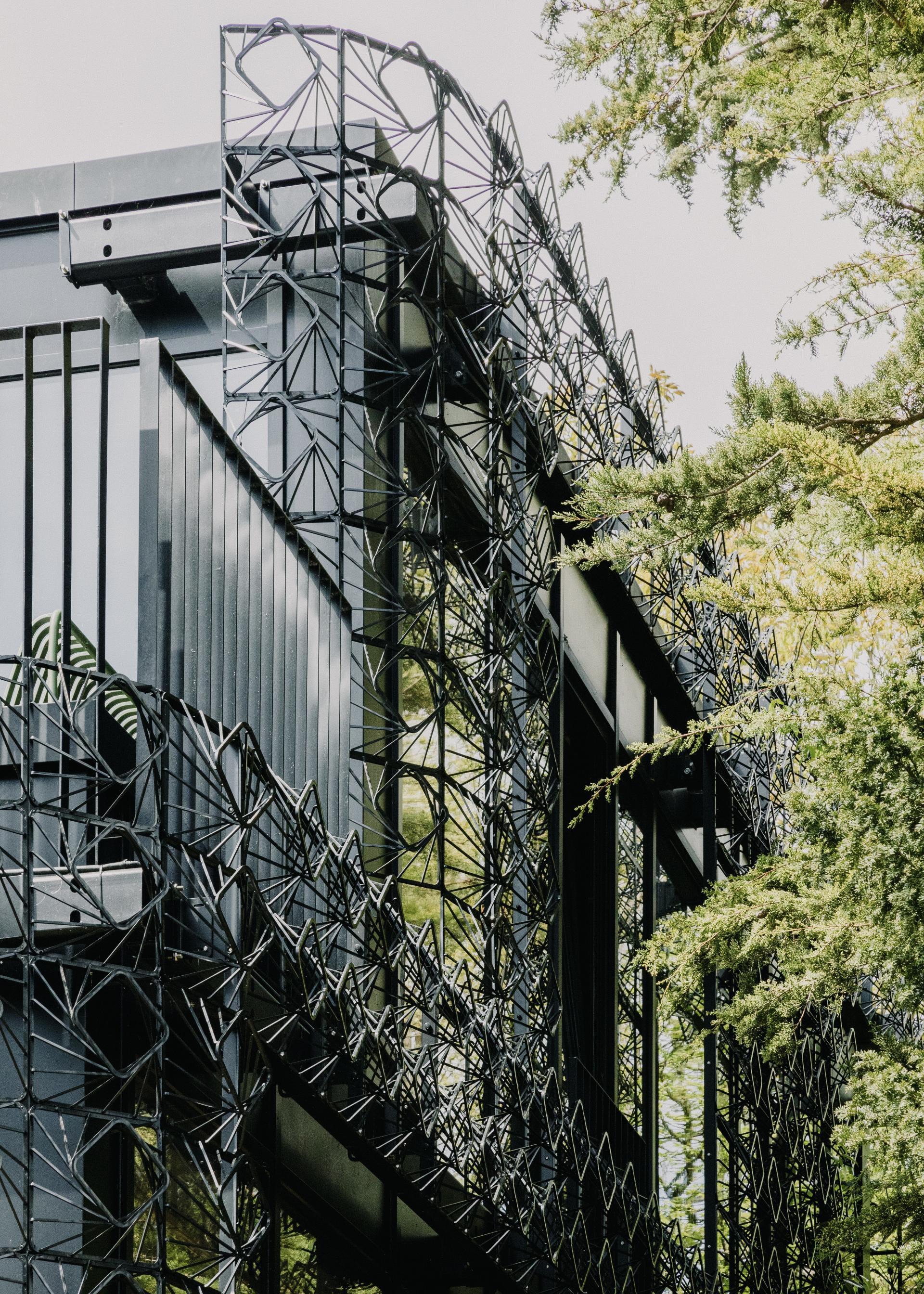 Contemporary black façade of Woven residential project, showcasing intricate sculptural design integrated with natural surroundings.