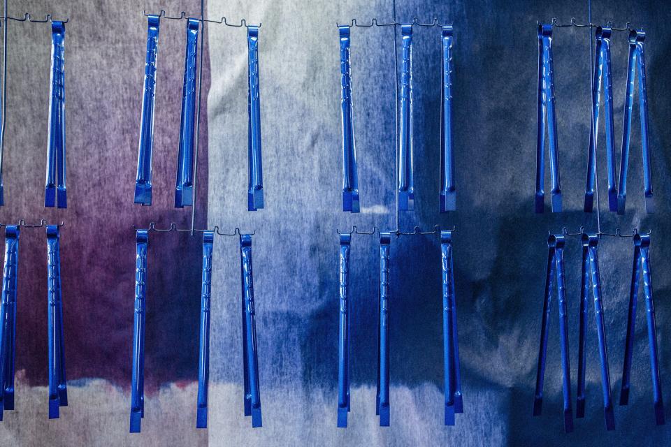 Metal-crafted blue straps hang against a textured backdrop, showcasing traditional craftsmanship from Tsubame-Sanjo at Japan House London.