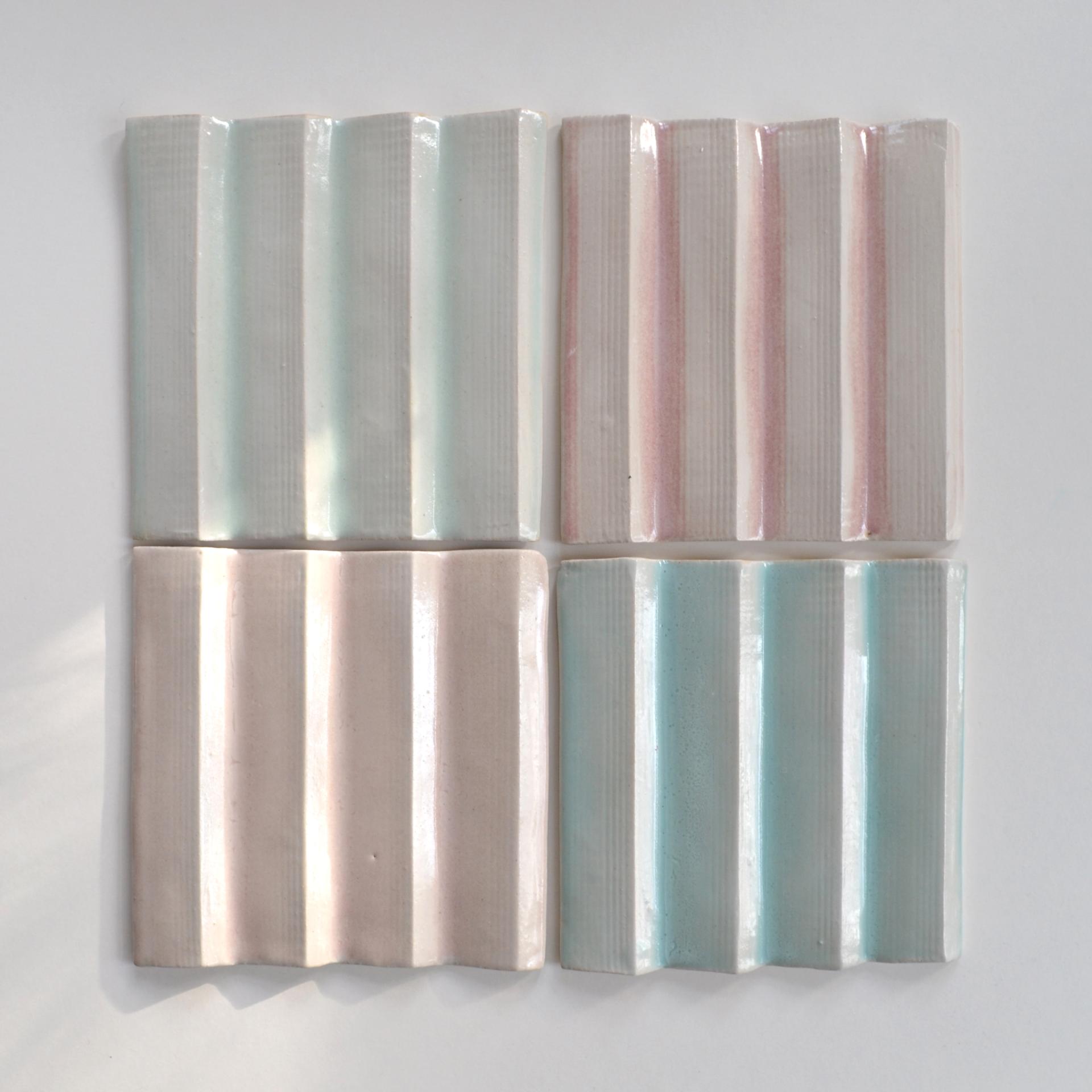 Textured ceramic tiles in pastel colors displayed in a grid pattern, highlighting contemporary ceramic design in architecture.