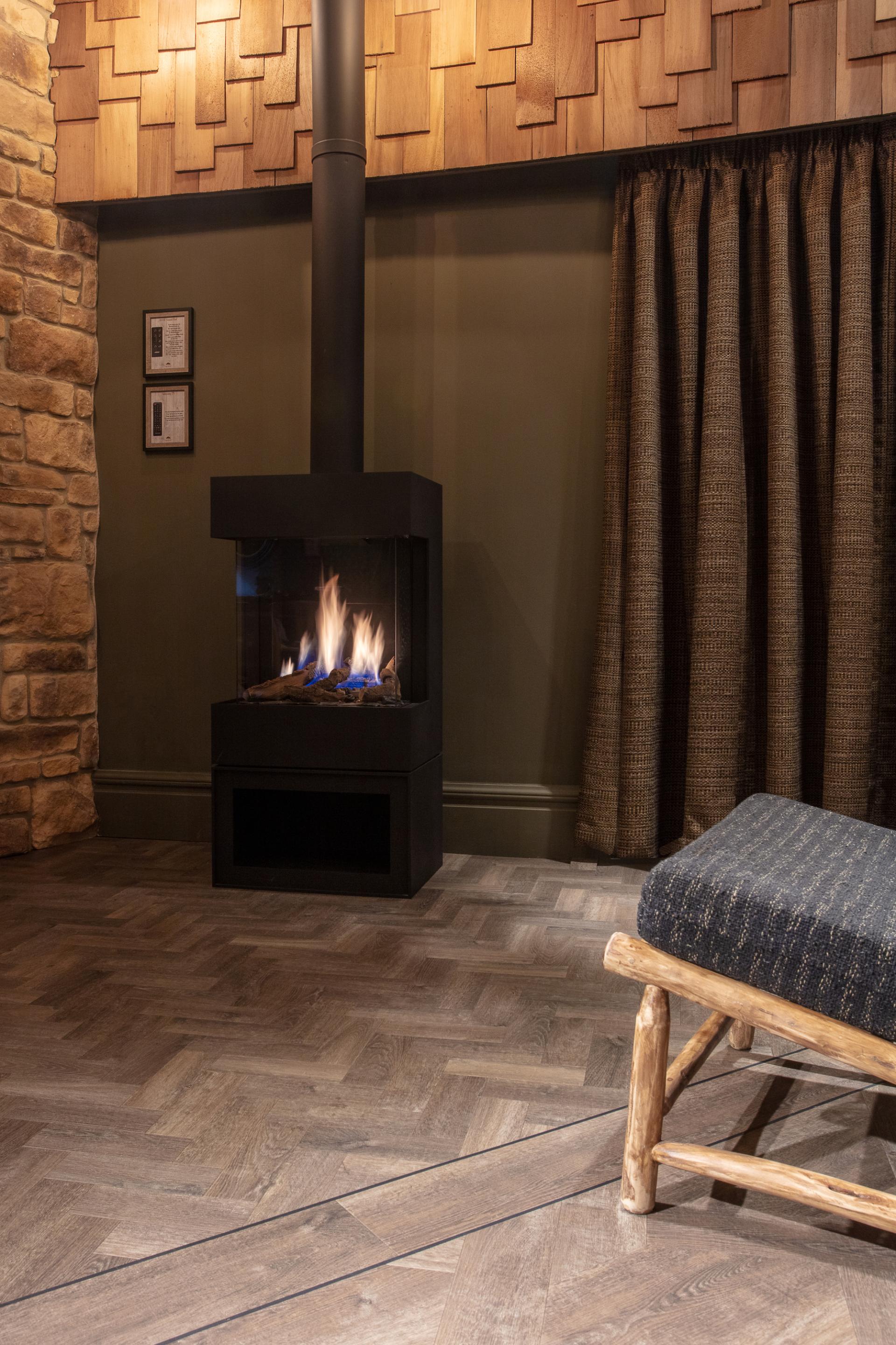 Cozy interior of the Dove Treehouse featuring a modern gas fireplace, wooden floor, and textured curtains.