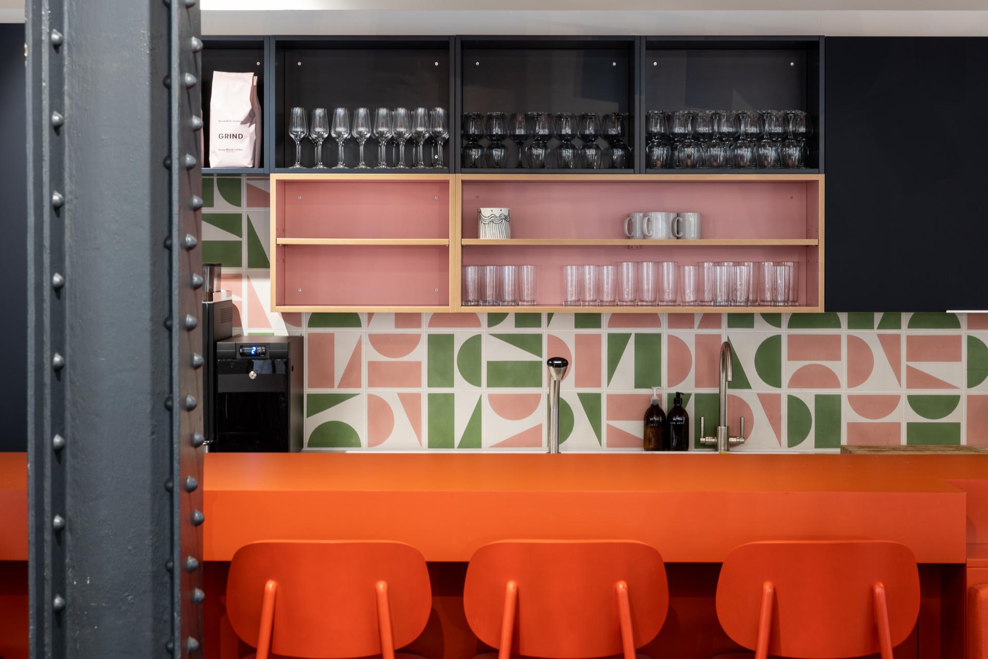 Colorful co-working kitchen featuring vibrant patterns, modern design, and stylish bar stools in an inviting space.