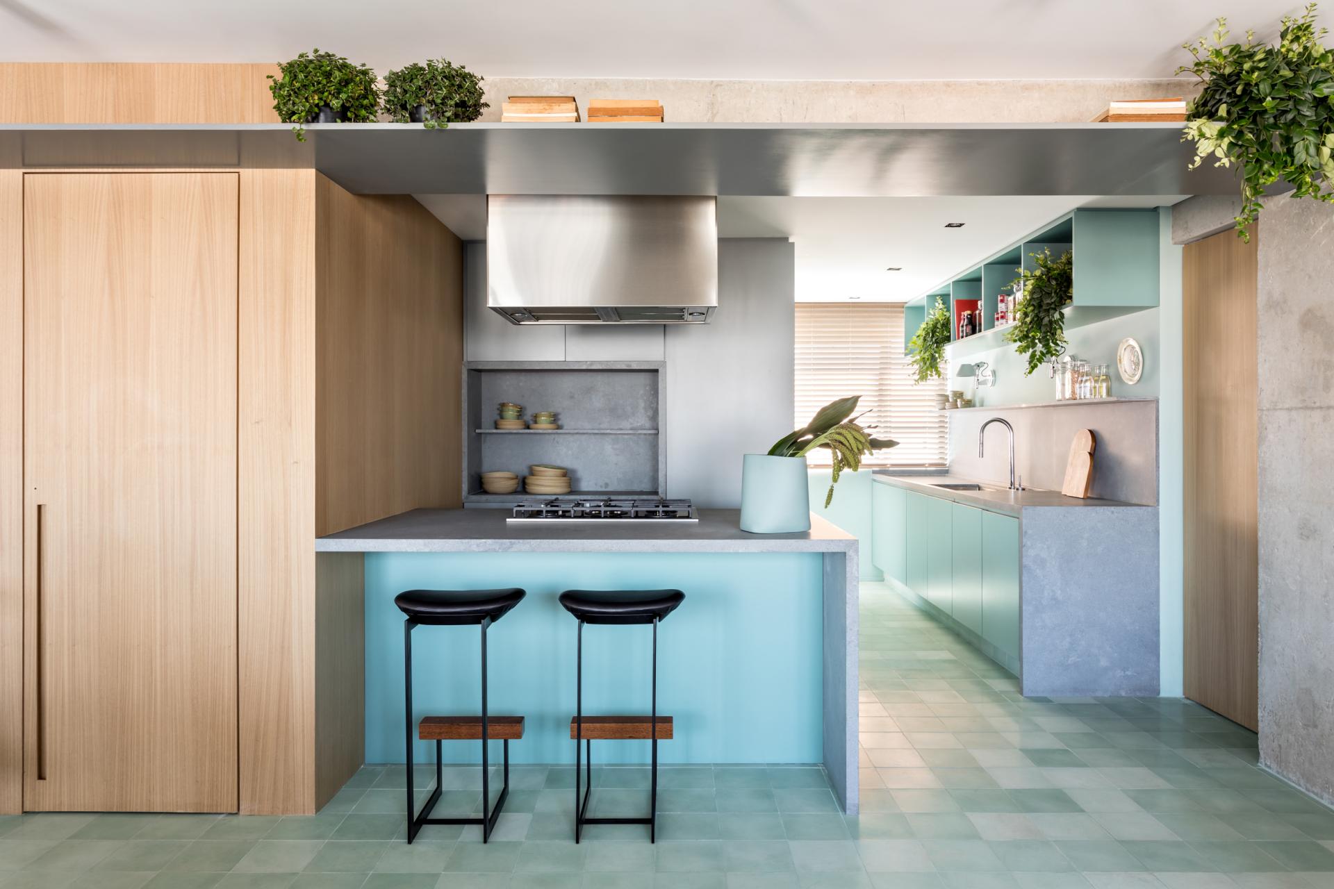 Modern kitchen design featuring turquoise cabinetry, concrete accents, and sleek appliances in a São Paulo apartment.