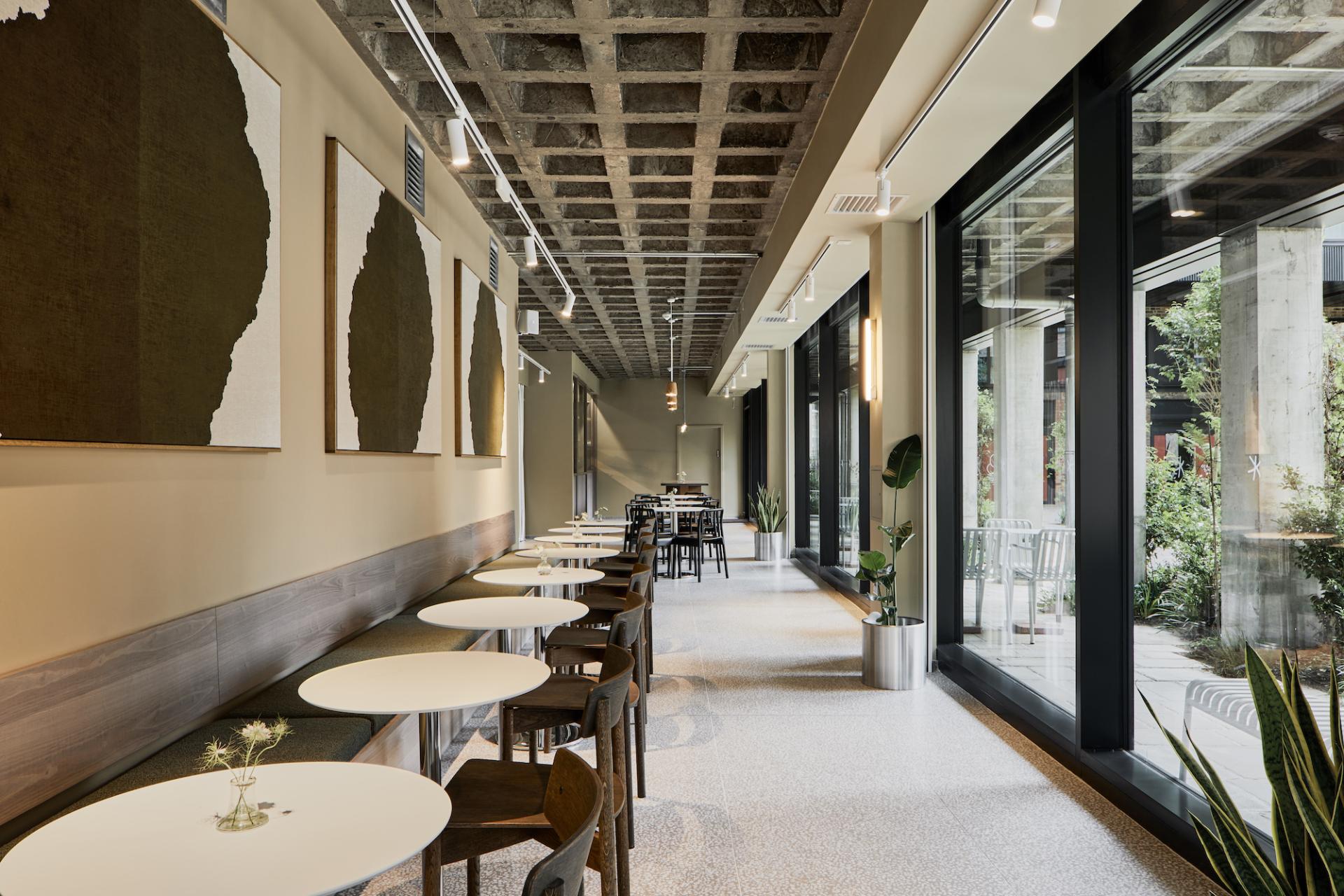Modern café interior featuring minimalist decor, natural light, and a blend of indoor plants at Pollen Bakery.