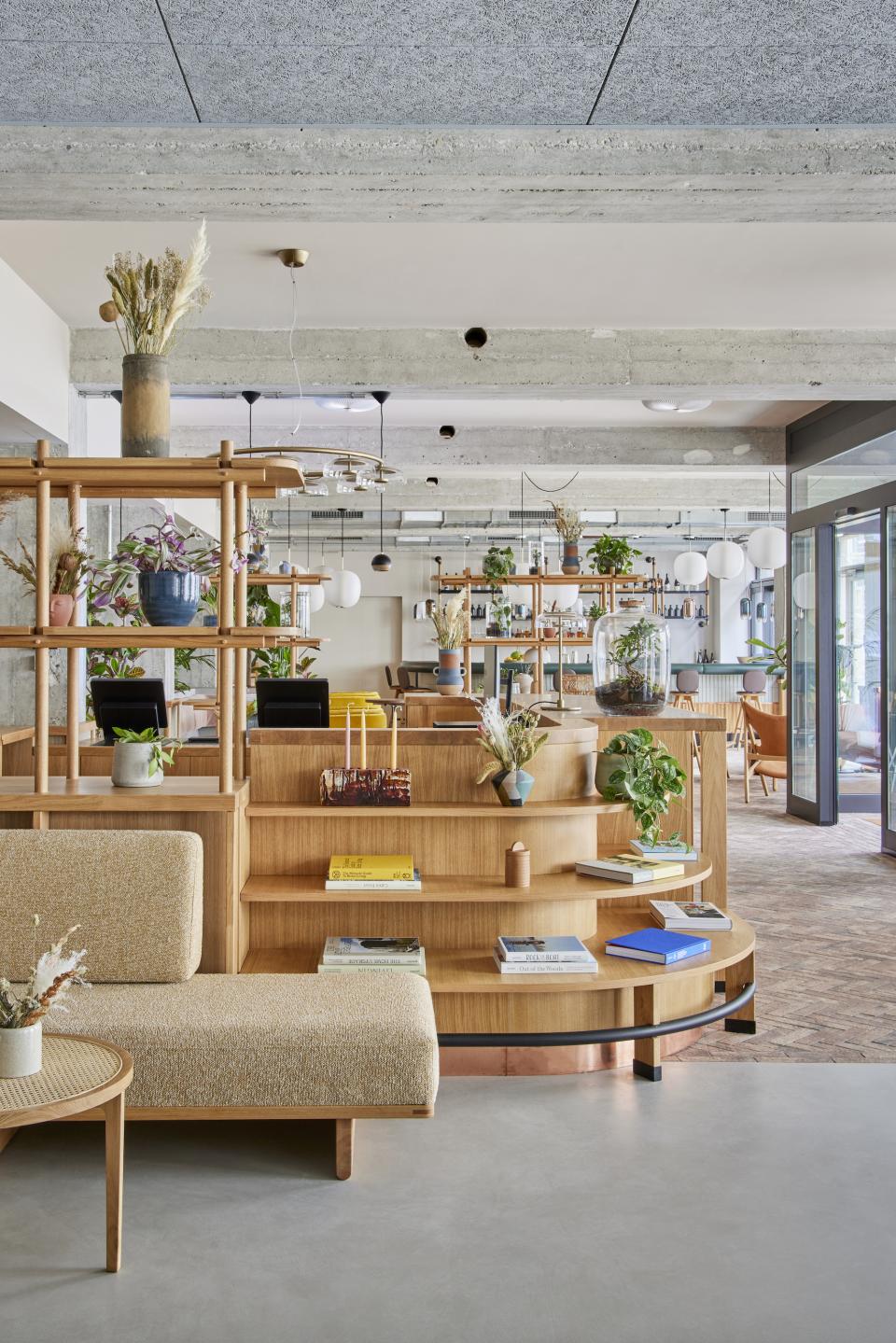 Modern lobby design of WunderLocke in Munich, featuring wooden shelving, plants, and cozy seating arrangements.