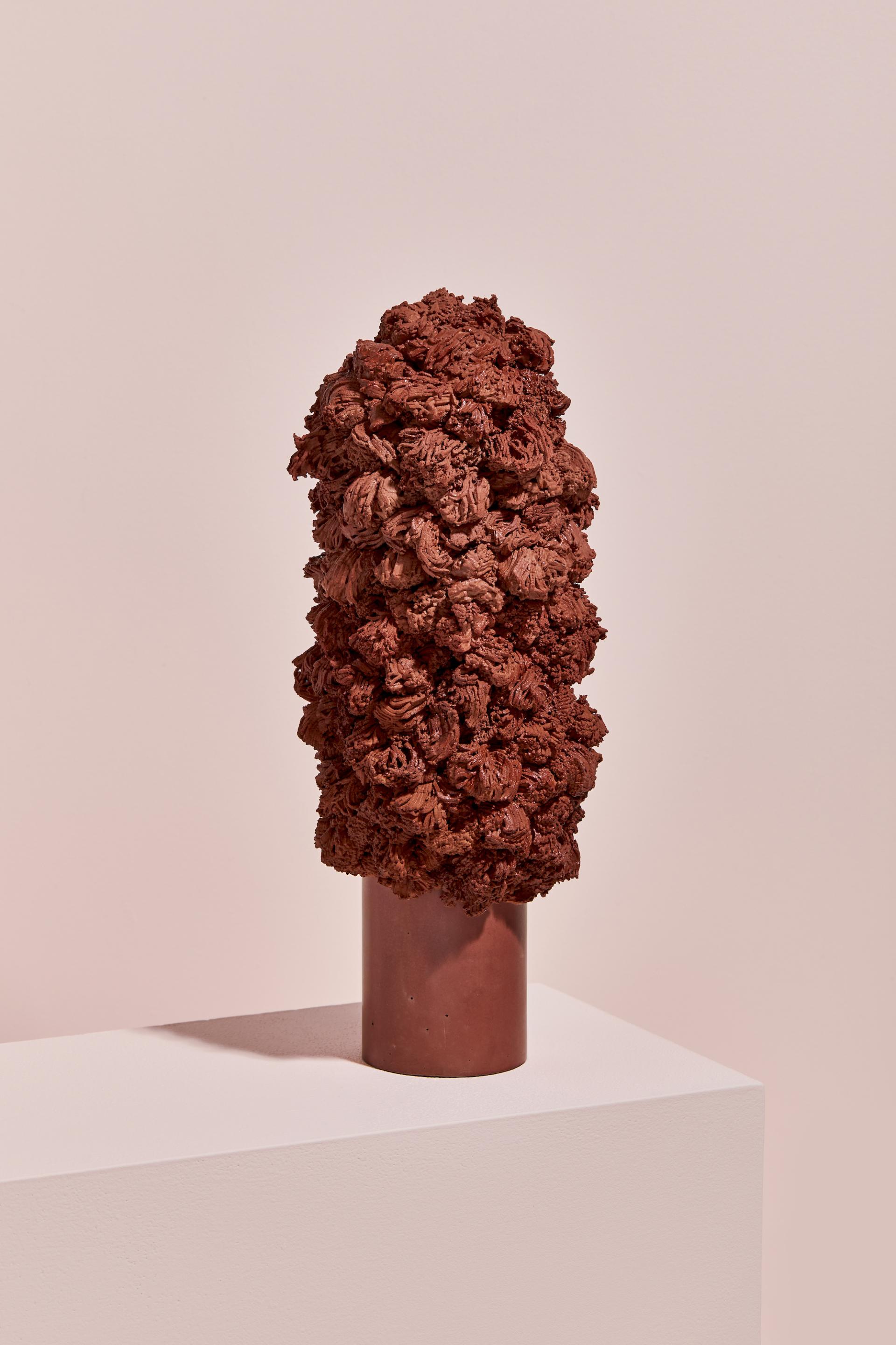 Sculptural artwork by Vic Wright featuring textured, reddish-brown ceramic forms on a minimalist pedestal.