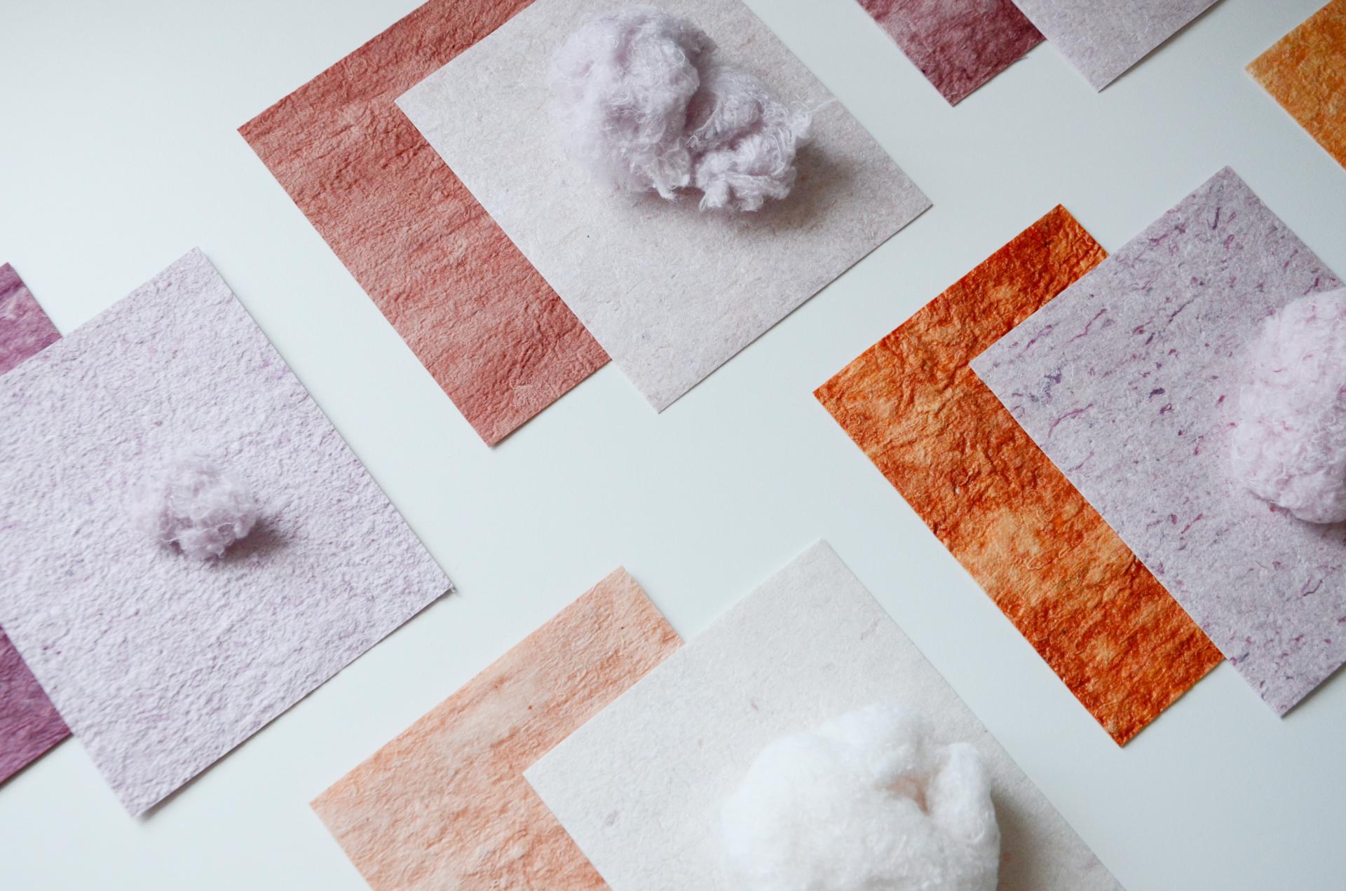 Colorful textured paper samples and fluffy fiber pieces represent innovative textile recycling concepts.
