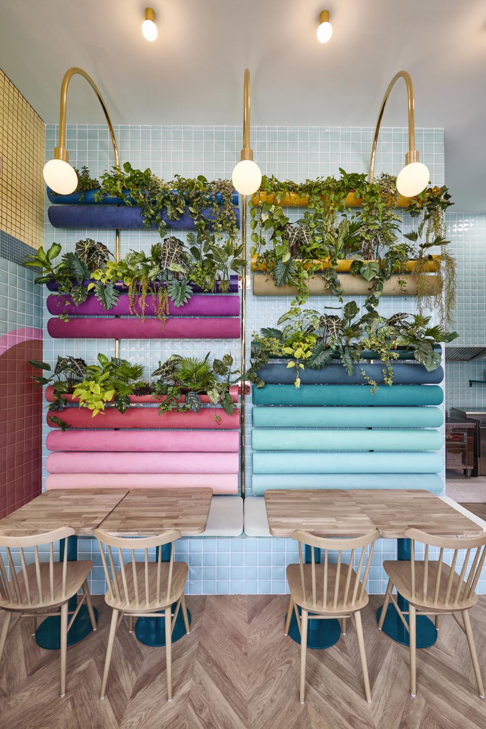 Contemporary interior design of Piada in Lyon featuring colorful fabric seating, plants, and natural wood tables, celebrating Italian aesthetics.