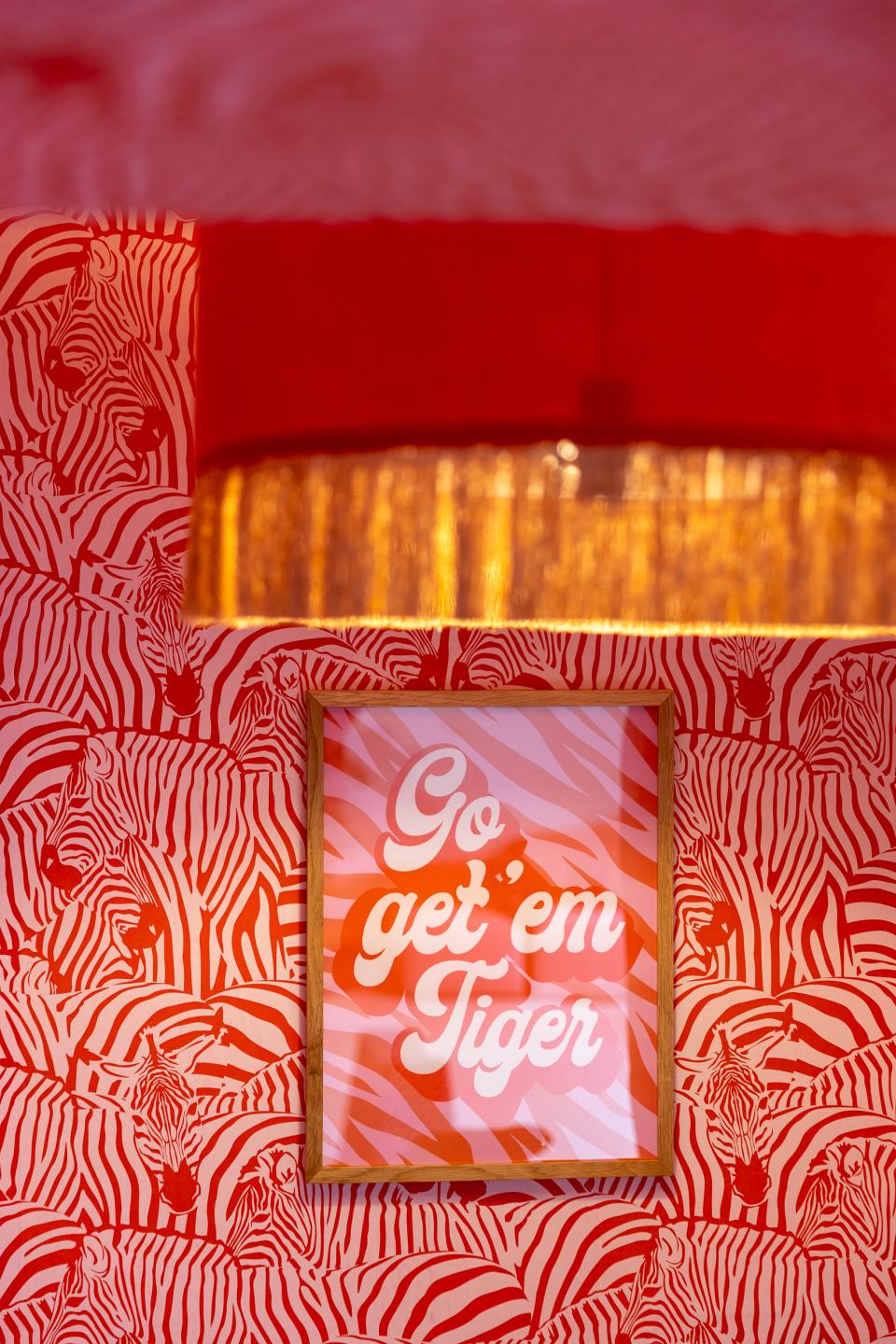 Vibrant zebra-patterned wallpaper featuring the motivational phrase "Go get 'em Tiger," enhancing the creative workspace's atmosphere.