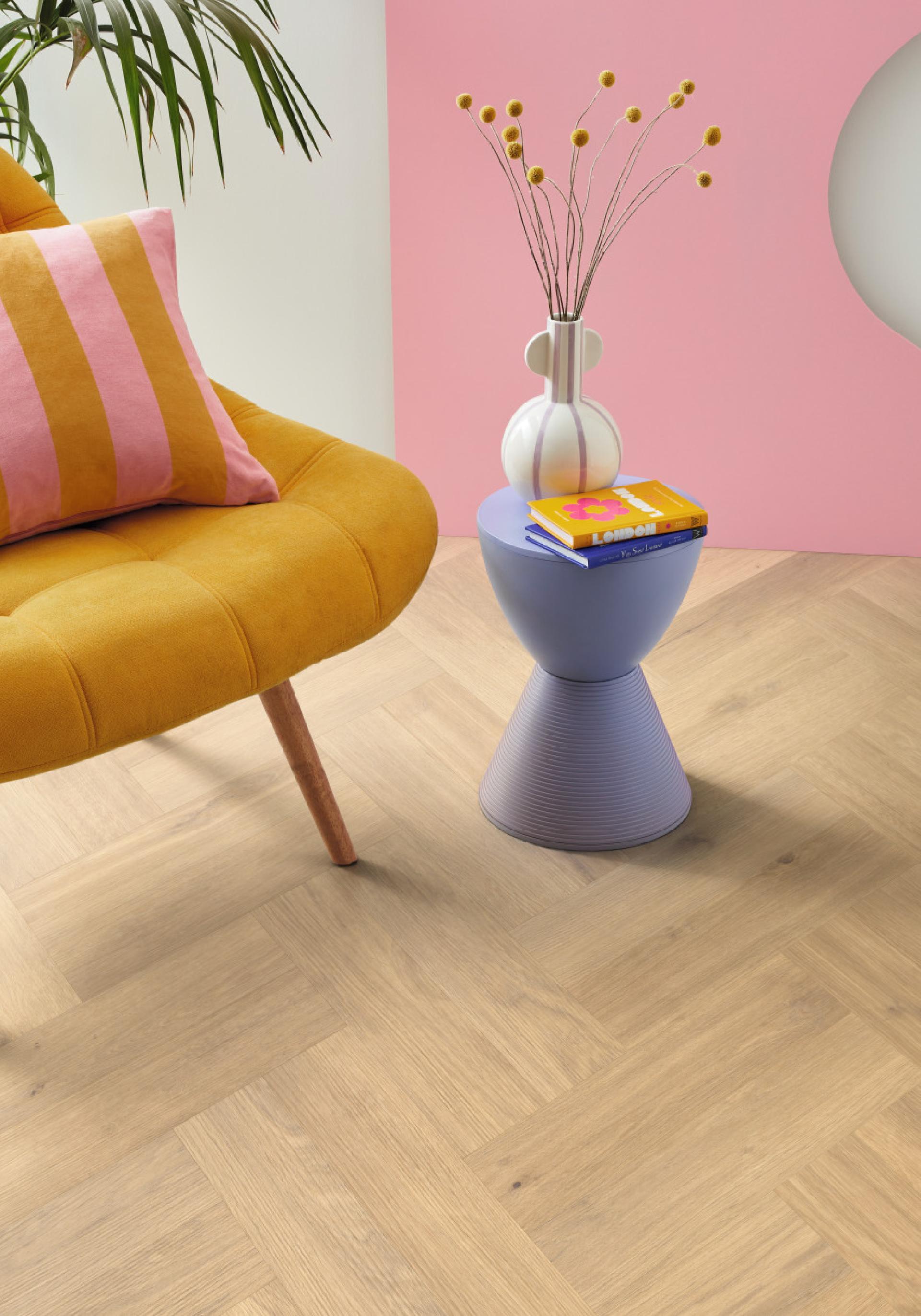 Elegant oak herringbone flooring complements a modern yellow lounge chair, colorful decor, and stylish accessories.