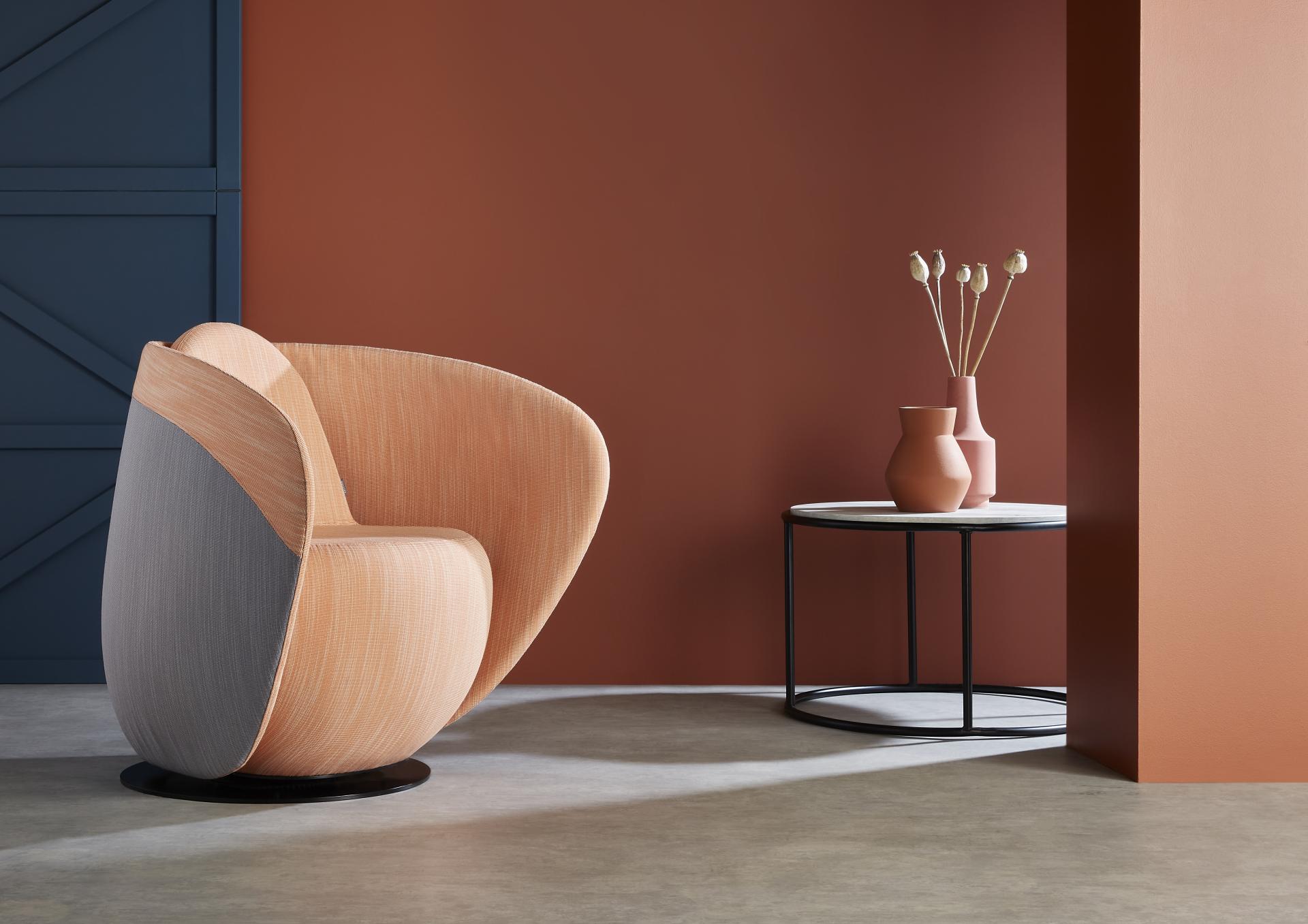 Rounded cocoon chair in calming tones, alongside minimalistic table and vases, enhancing tranquil workspace aesthetics.