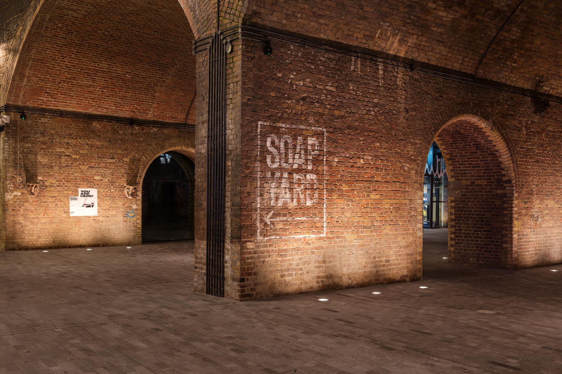 Exposed brick arches in Borough Yards, featuring a 'SOAP YARD' sign and ambient lighting in a vibrant cultural space.