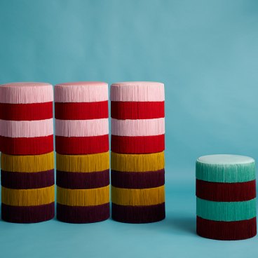 Colorful vintage-inspired stools designed by Masquespacio and Houtique, featuring layered fringed textures against a pastel background.