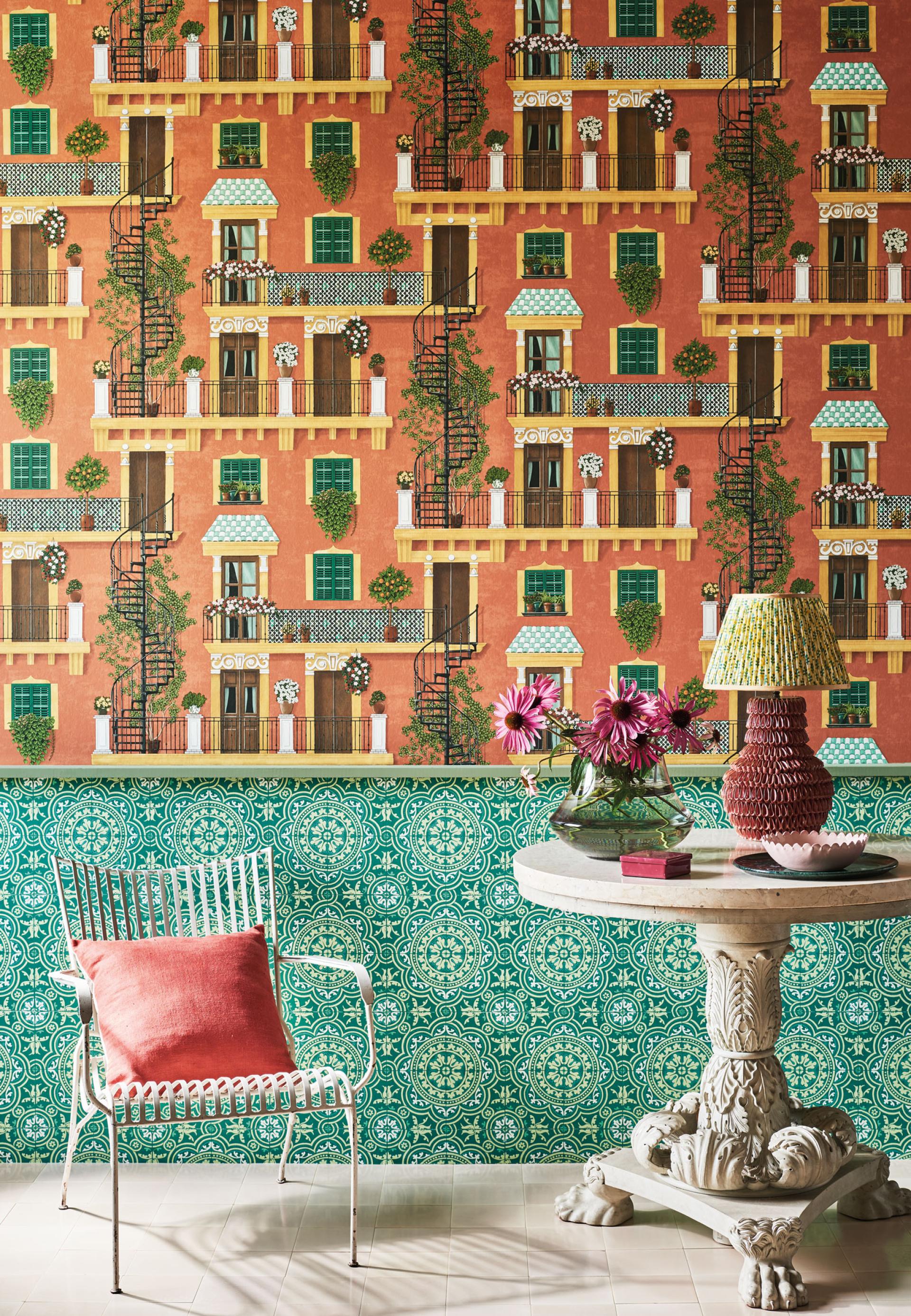 Vibrant Seville wallpaper featuring intricate balconies and green accents, complemented by decorative furniture and floral arrangements.