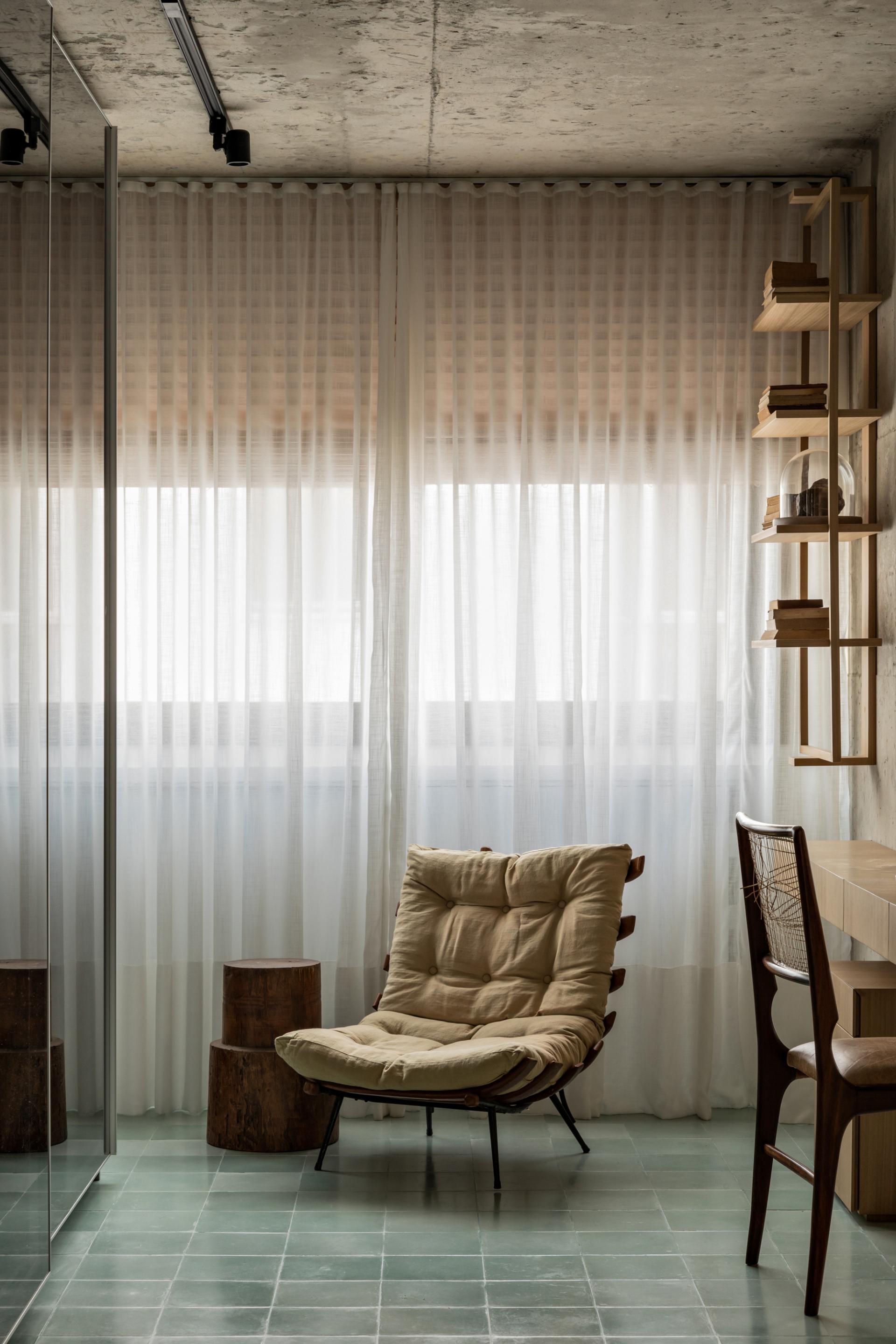 Cozy corner in a modern São Paulo apartment featuring a vintage chair and natural light filtering through sheer curtains.