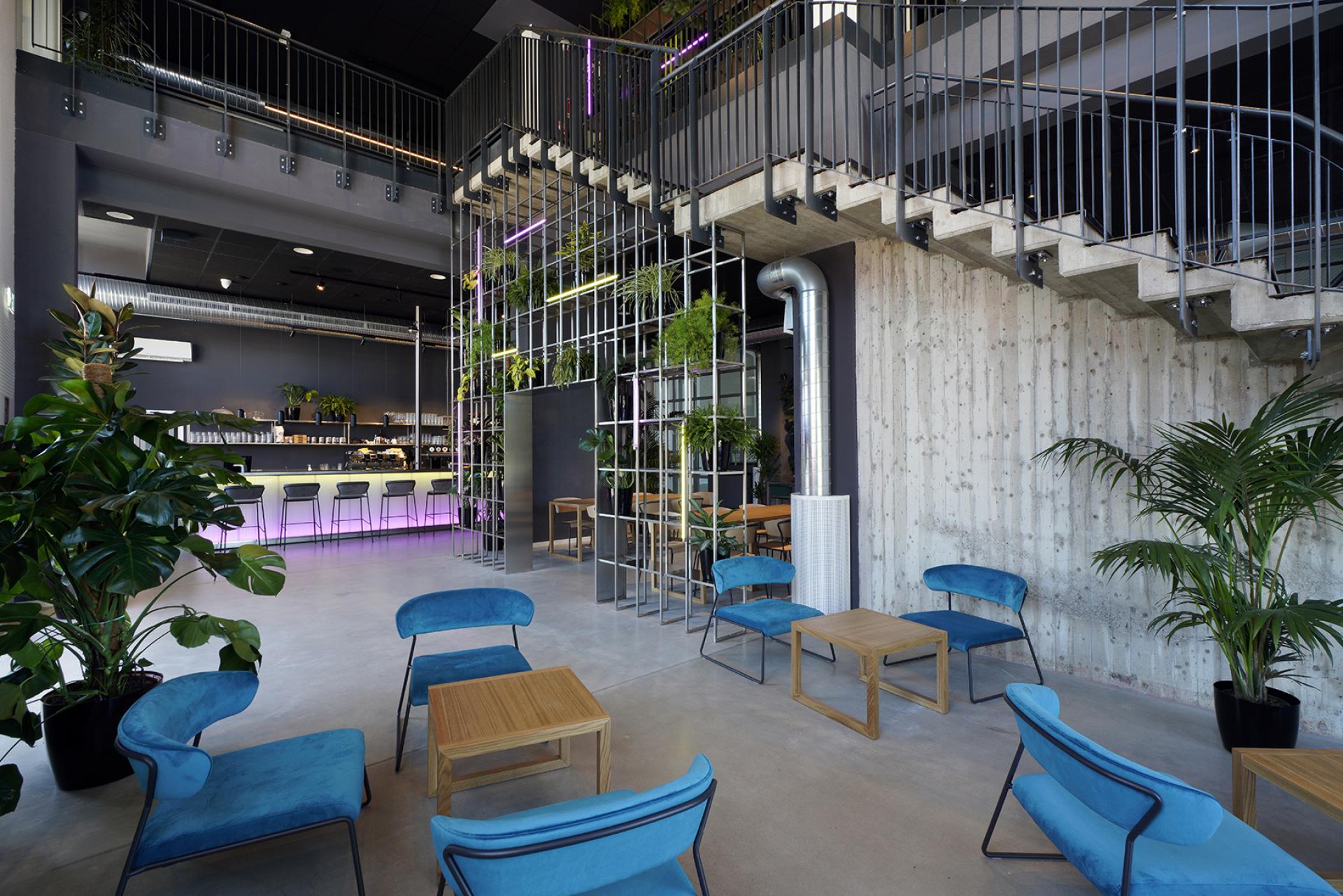 Modern interior of Daste in Bergamo, featuring vibrant decor, plants, and a welcoming seating area for community engagement.