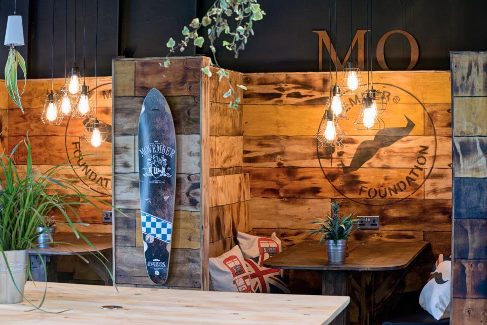 Industrial-inspired design of Movember Foundation’s London office, featuring wooden walls, pendant lights, and vibrant decor.