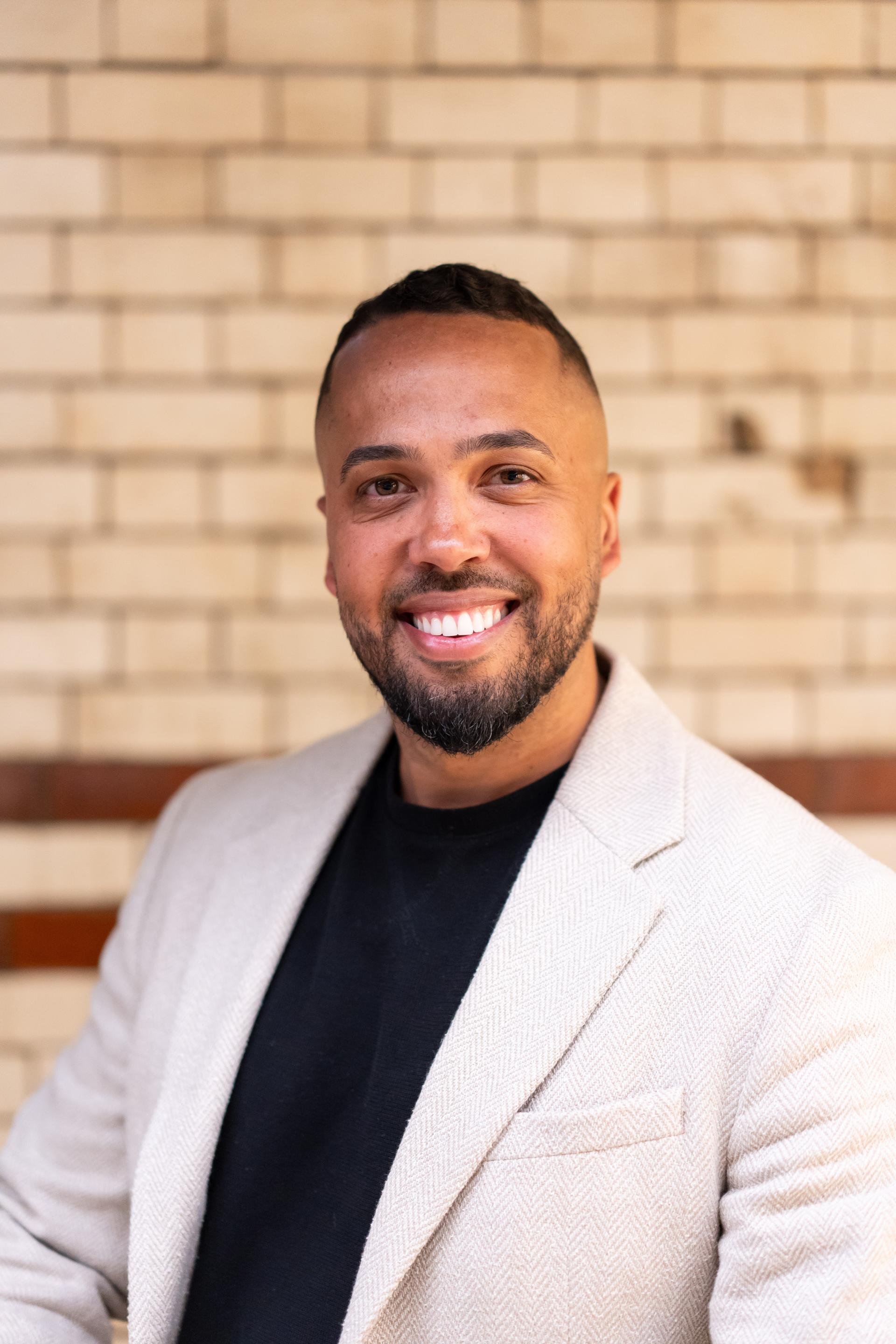 Smiling man in a blazer, emphasizing EDI discussions on creating inclusive workplace culture.