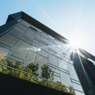 Modern building with reflective glass windows, showcasing sustainable architecture under bright sunlight, emphasizing net zero carbon design.