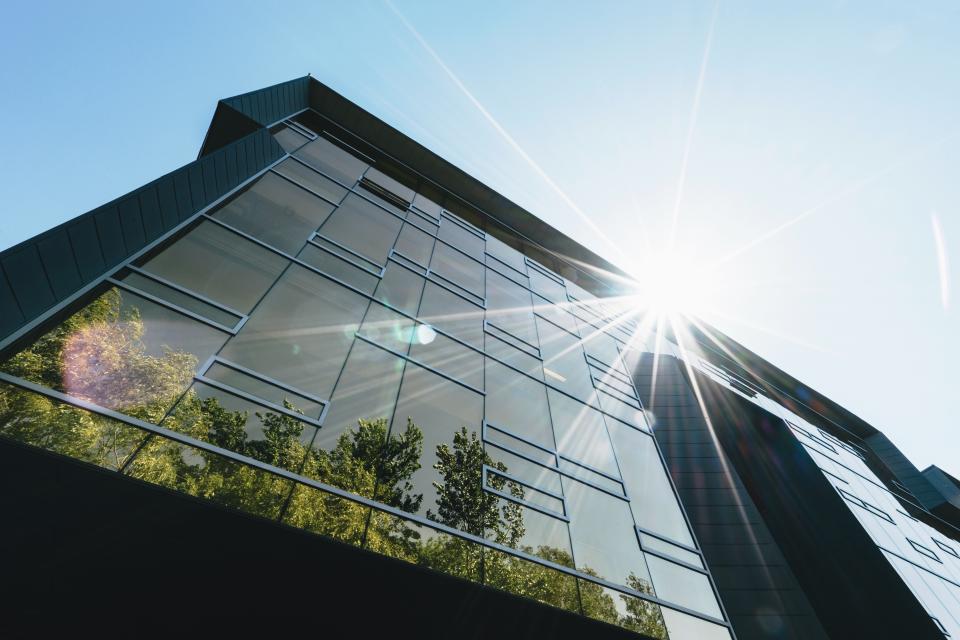 Modern building with reflective glass windows, showcasing sustainable architecture under bright sunlight, emphasizing net zero carbon design.
