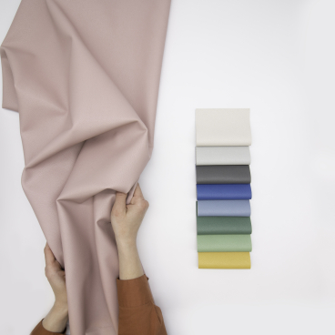 A person holds a soft, recycled performance fabric swatch, showcasing various colors for innovative sustainable design.
