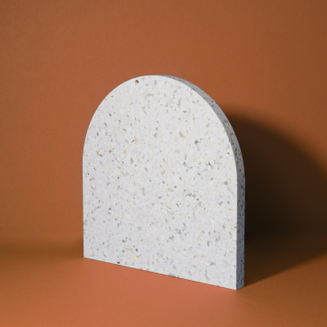 A textured, white arch-shaped panel made from Smile Plastics’ eco-friendly material named Heron, set against a brown background.
