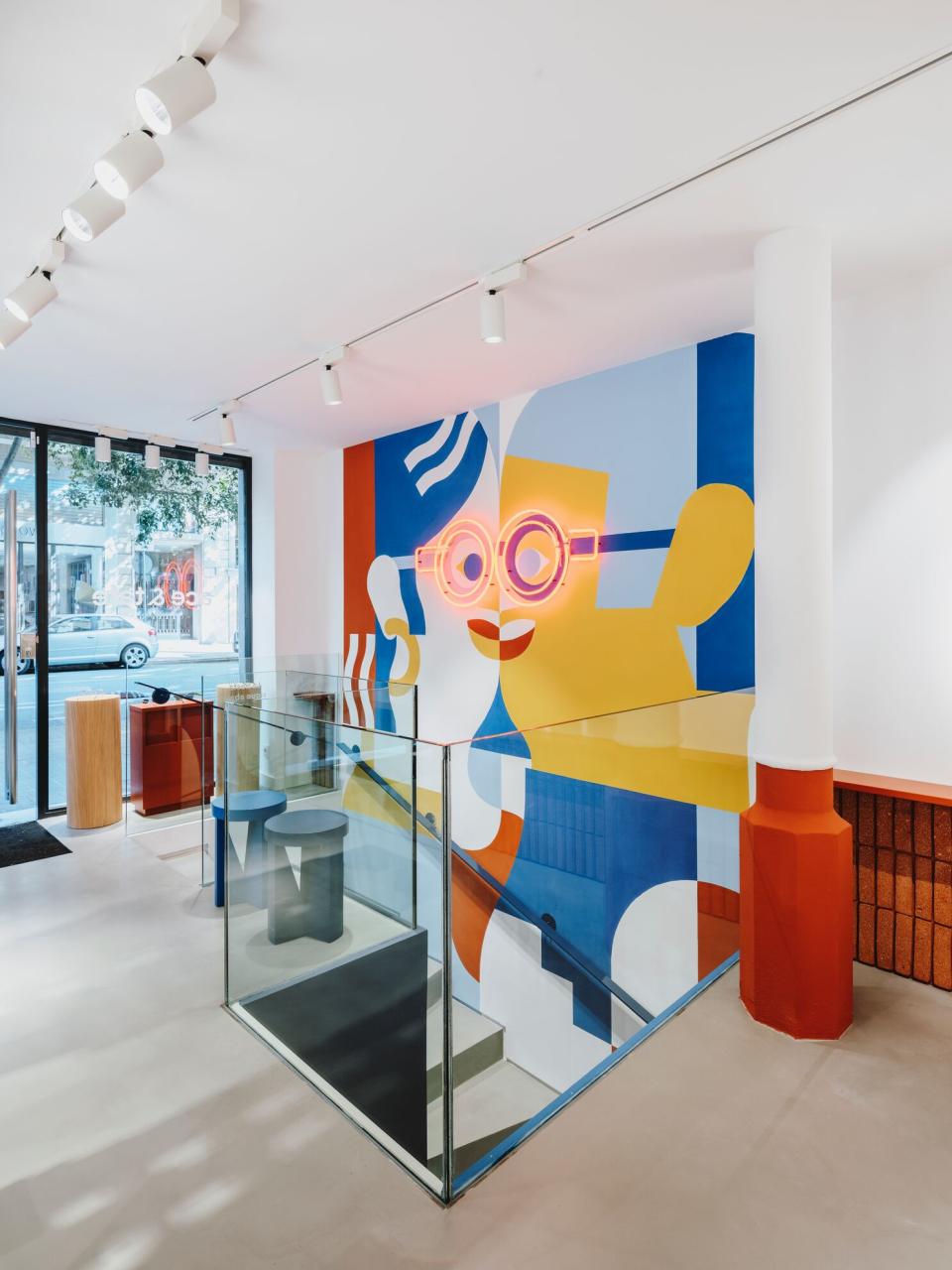 Vibrant interior of ACE & TATE Barcelona featuring colorful wall art and modern furniture that emphasizes sustainability.