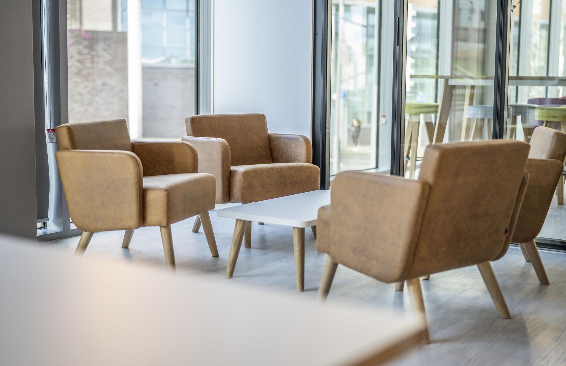 Cozy brown armchairs with a white table, designed for flexible office spaces at AMH Workspace project.