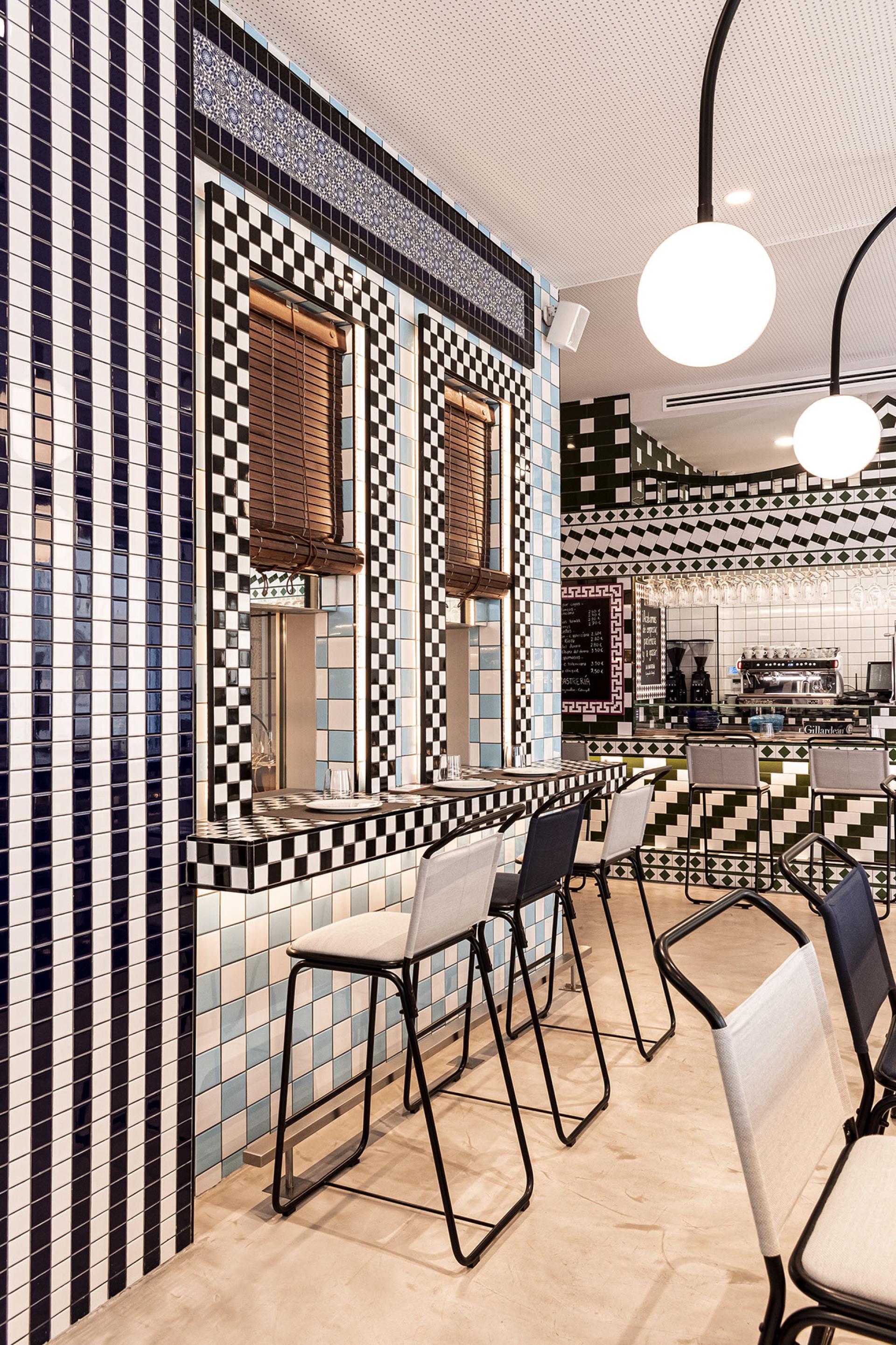 Colorful tiled walls and modern bar seating in the stylish interior of La Sastrería restaurant in Valencia.