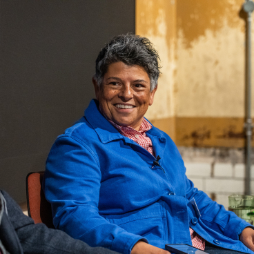 A smiling woman in a blue jacket participates in a discussion about the evolving workplace dynamics.