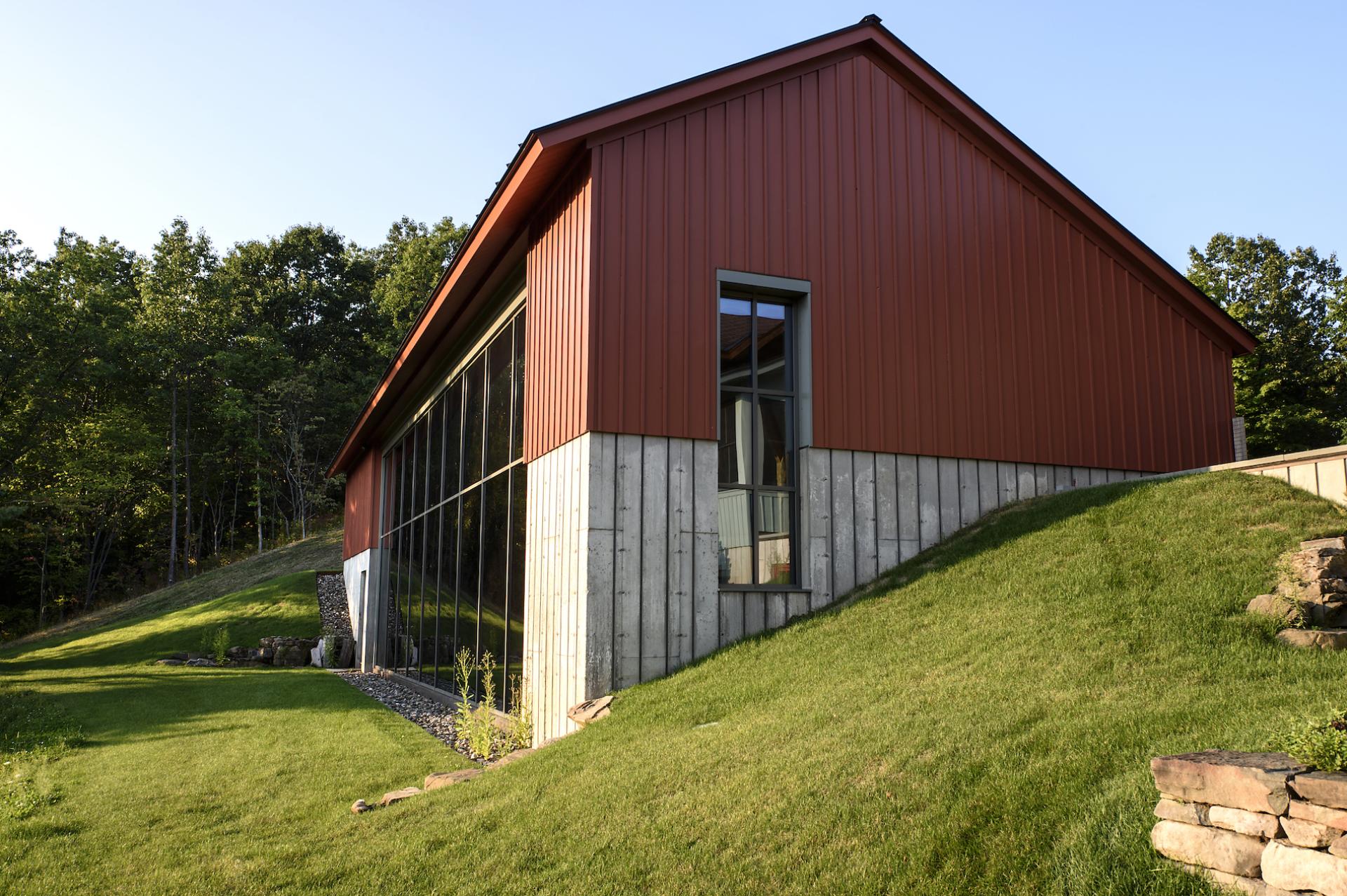 Modern pool house in Old Chatham, NY, featuring a sleek design, expansive windows, and lush surrounding greenery.