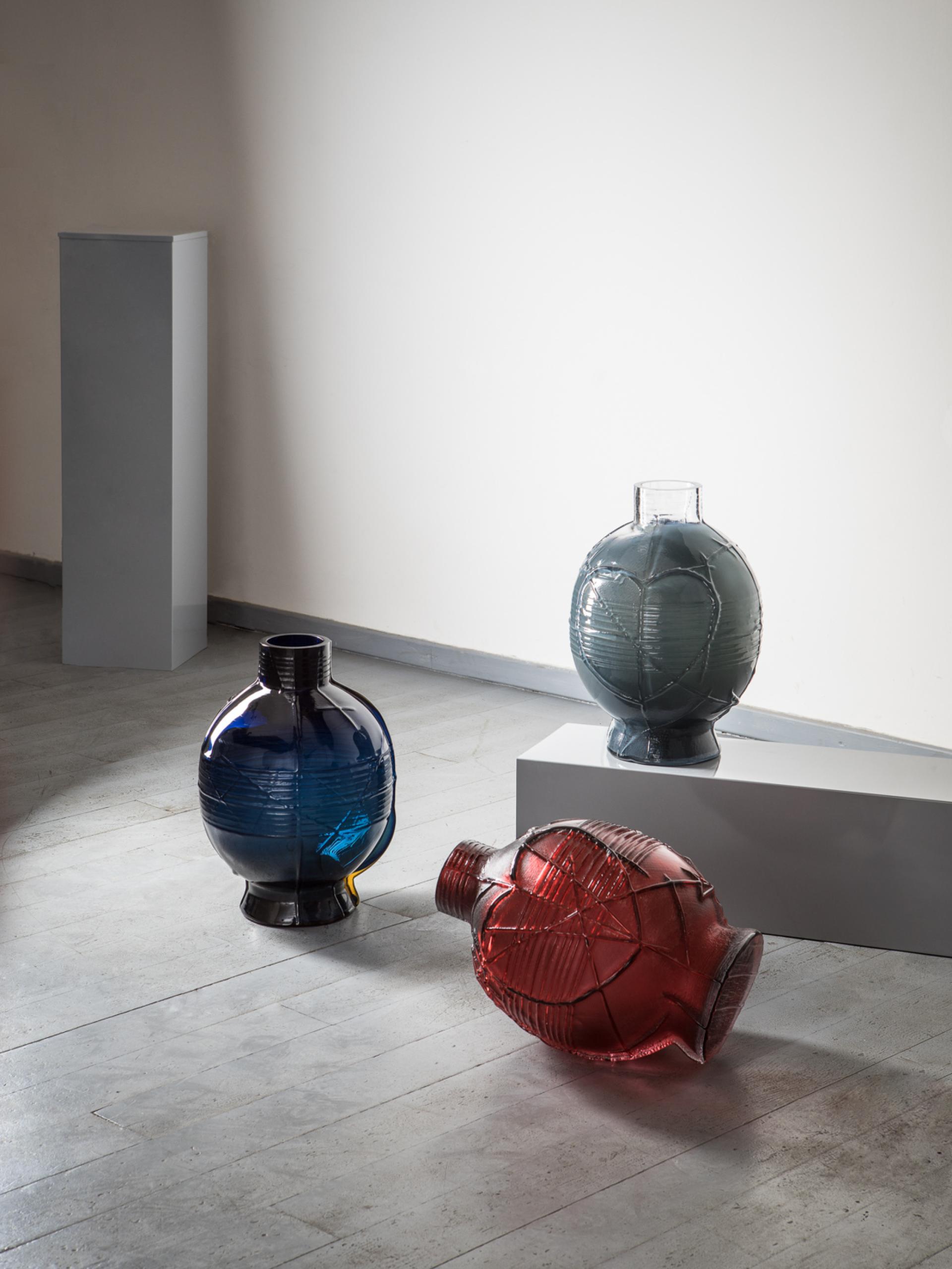 Artistic glass vases in blue, green, and red showcased at the London Design Fair, highlighting the beauty of transparency.