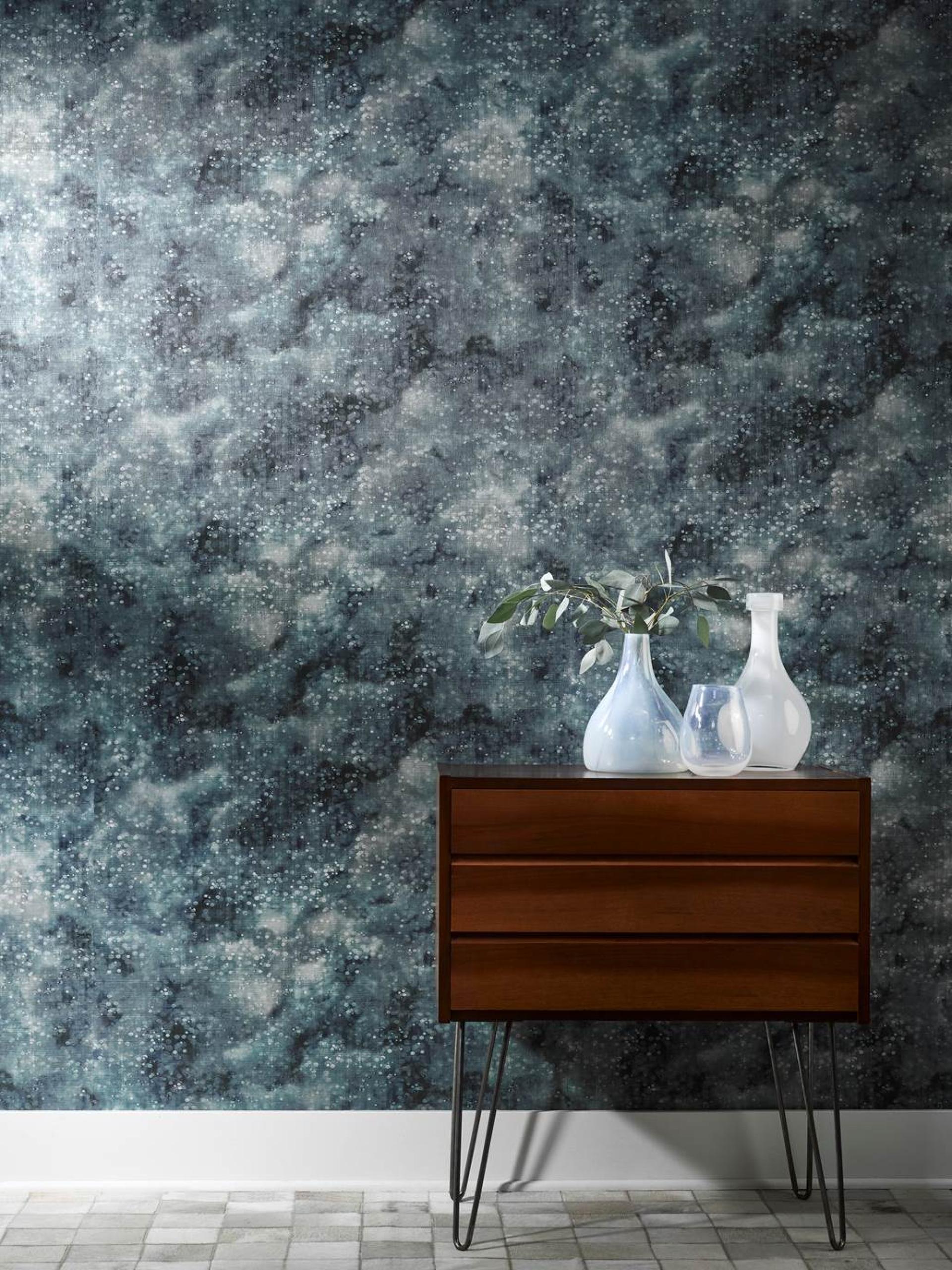 David Rockwell's fabric and wallcovering collection featuring a textured dark blue abstract wall design with a modern wooden dresser.