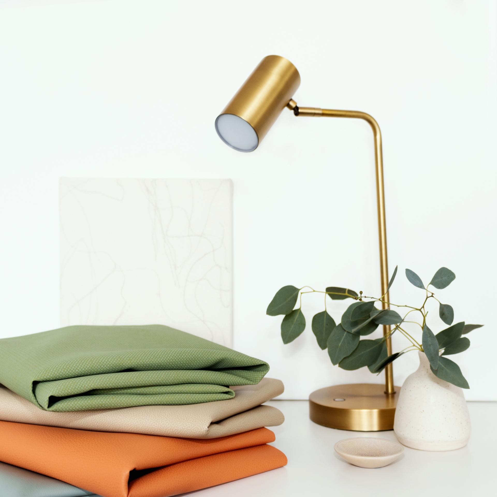 Textiles in soothing colors stacked neatly with a modern lamp and plant, representing Ultrafabrics’ Mindfulness Colour Palette.