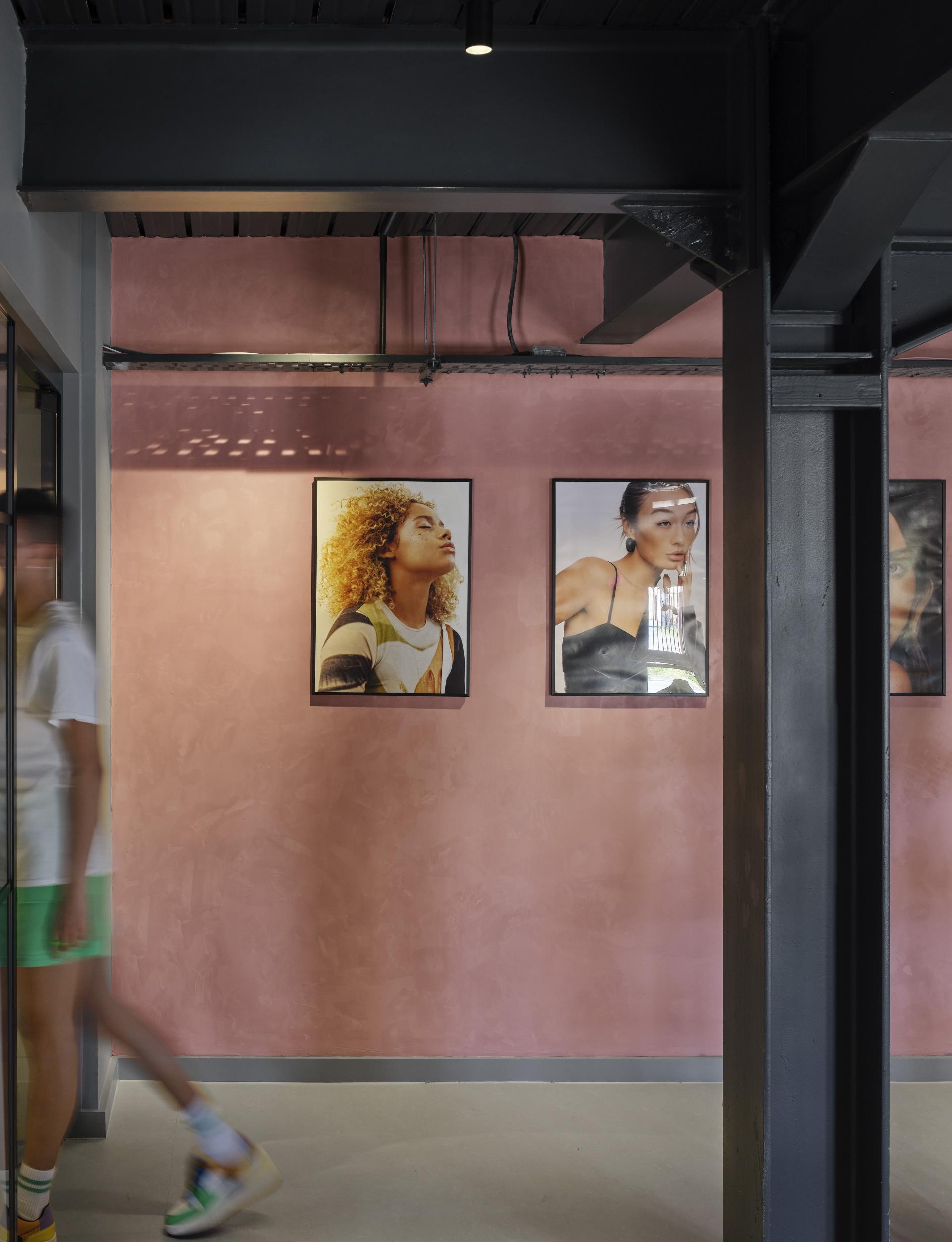 Stylish interior of J’adore Models' new HQ, featuring artful portraits against a pink wall, showcasing modern design.
