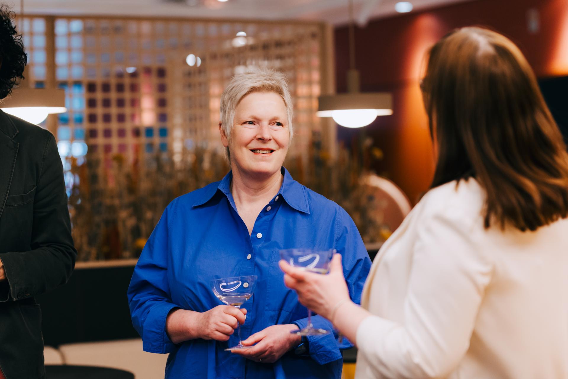 Discussion on neurodiversity at Material Source Studio, featuring participants engaged in conversation with drinks in hand.
