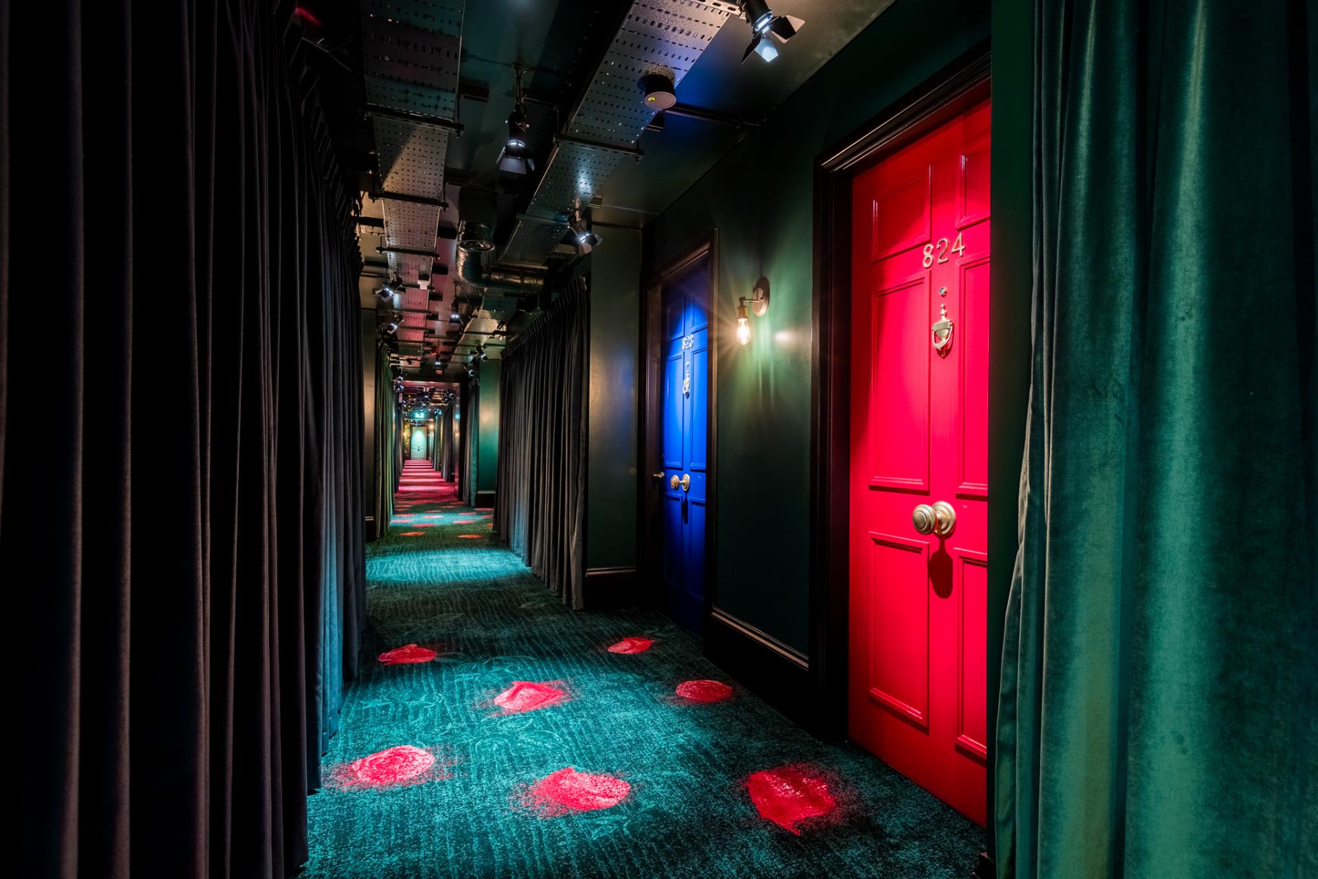 Vibrant hotel corridor in nhow London, featuring colorful doors and unique carpet design, reflecting innovative architecture.